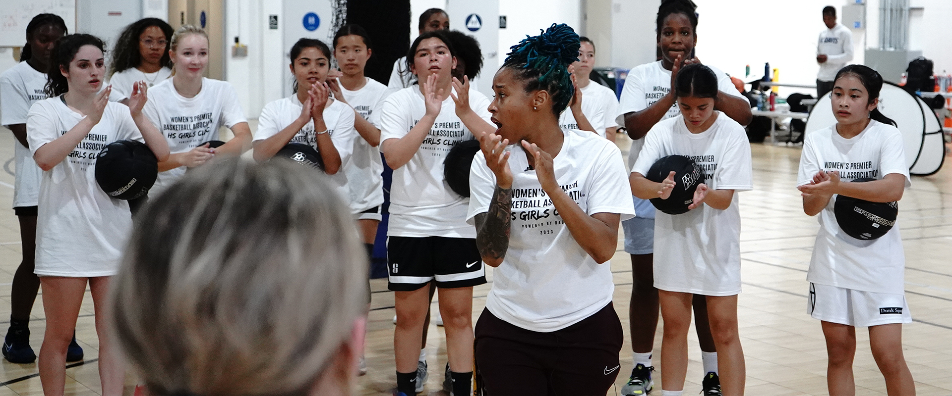 Group of women in a gym, getting ready to play basketball.