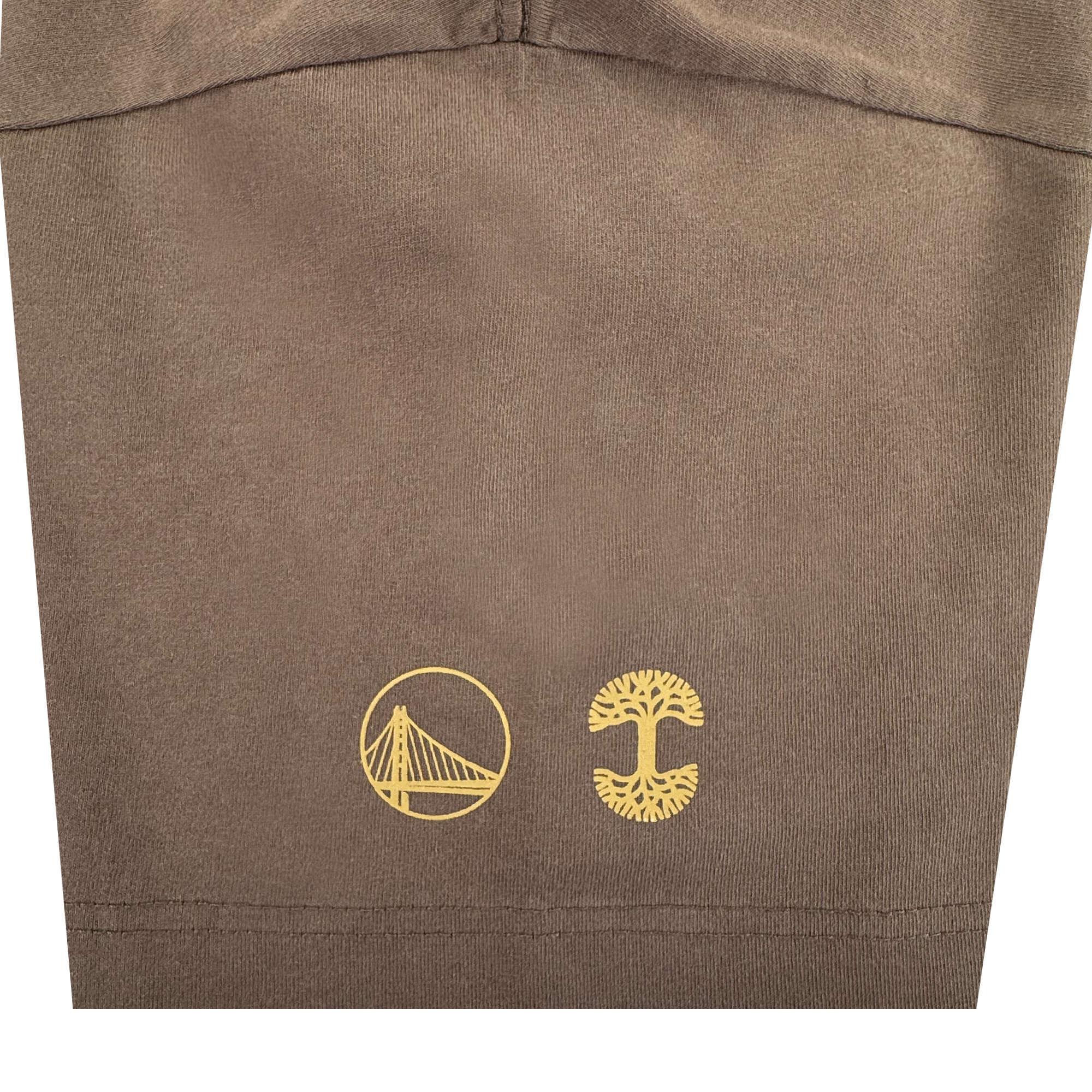 Close-up of the brown Arched Black-Letter Tee by GSW, showing two yellow icons near the hem: a stylized suspension bridge and a tree with wide roots and branches. Stitch line visible.