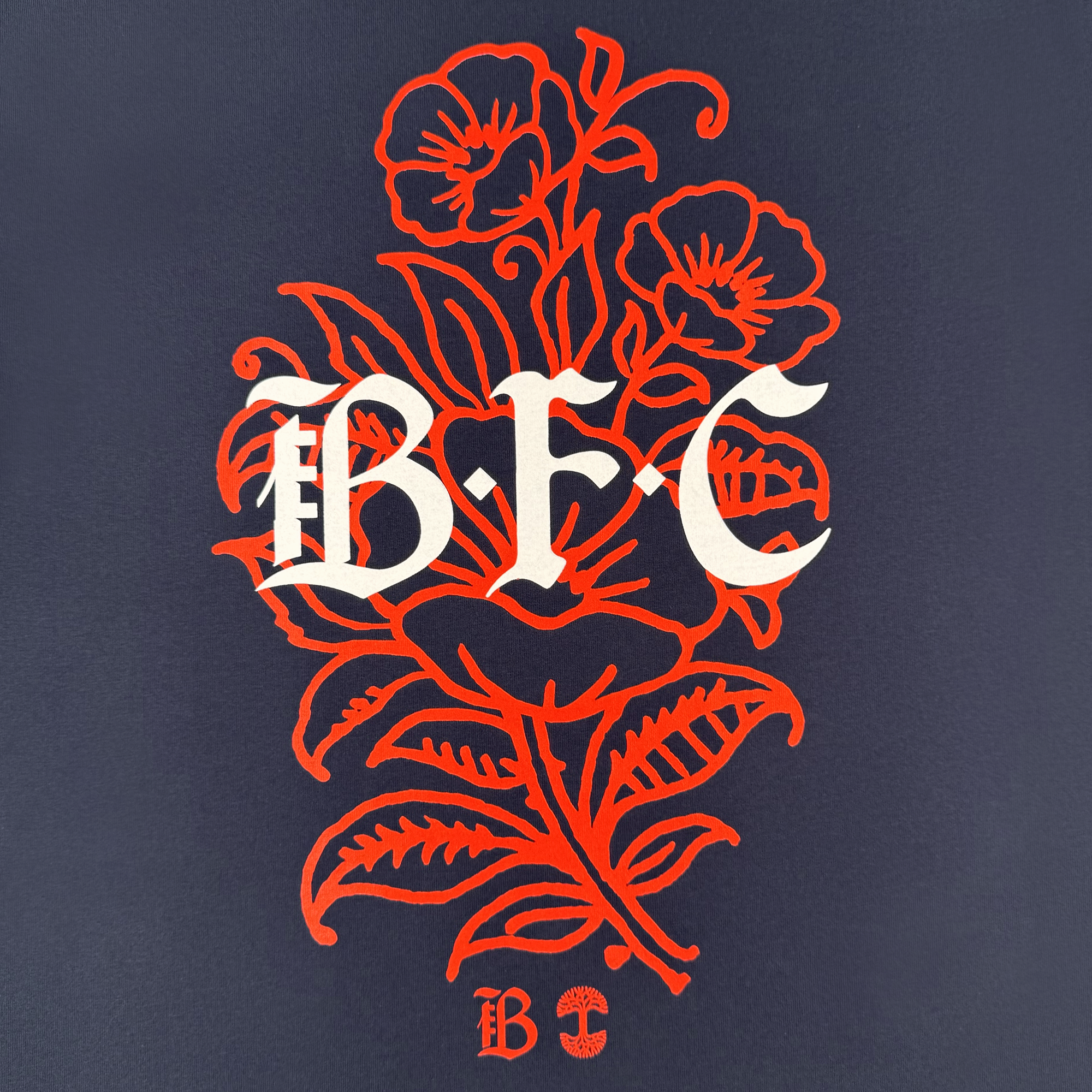 A stylized illustration of red poppies and leaves on a dark background with bold white "BFC" decorates the Bay FC Flora Tee, making it a perfect classic fit t-shirt for Bay FC fans.