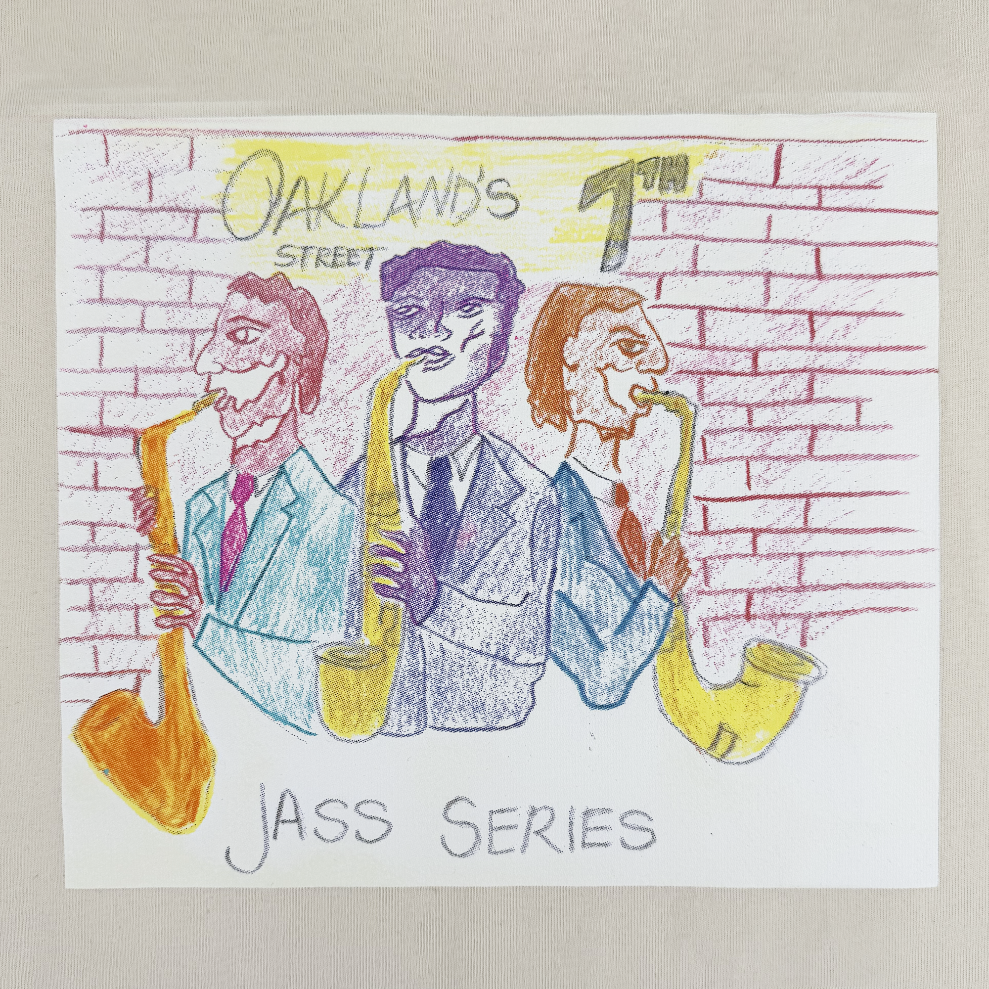 The Oaklandish 7th St. Players Tee features a colorful, crayon-style drawing of three men in suits playing saxophones before a red brick wall, printed on a 100% cotton classic fit t-shirt. Expressive faces and bold lines complete the design.