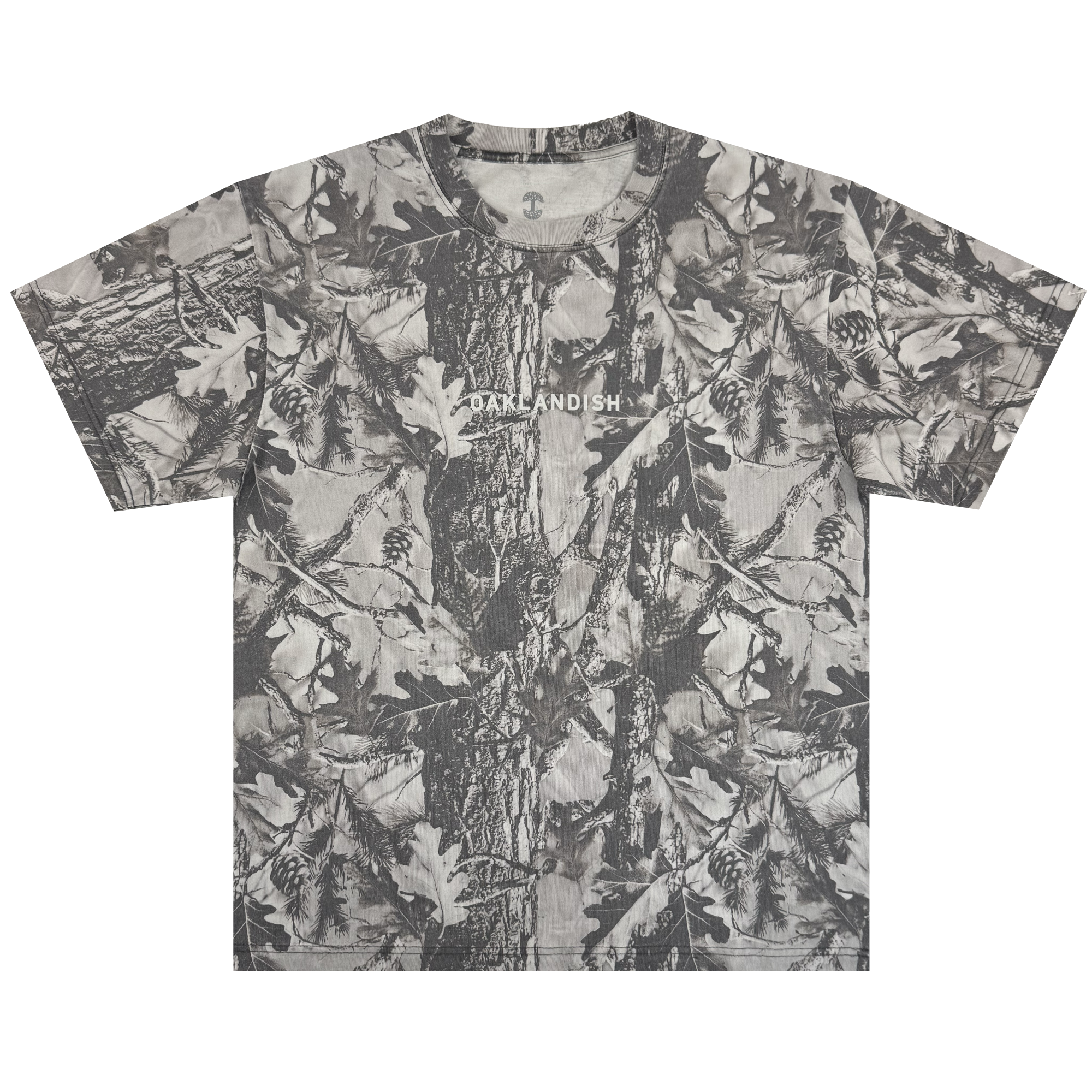 The Oaklandish Classic Logo Tee by Oaklandish is a heavyweight, short-sleeve oversized t-shirt in grey forest camo with tree bark, oak leaves, and pinecones. "OAKLANDISH" is printed in white across the chest. Shirt shown flat on a white background.