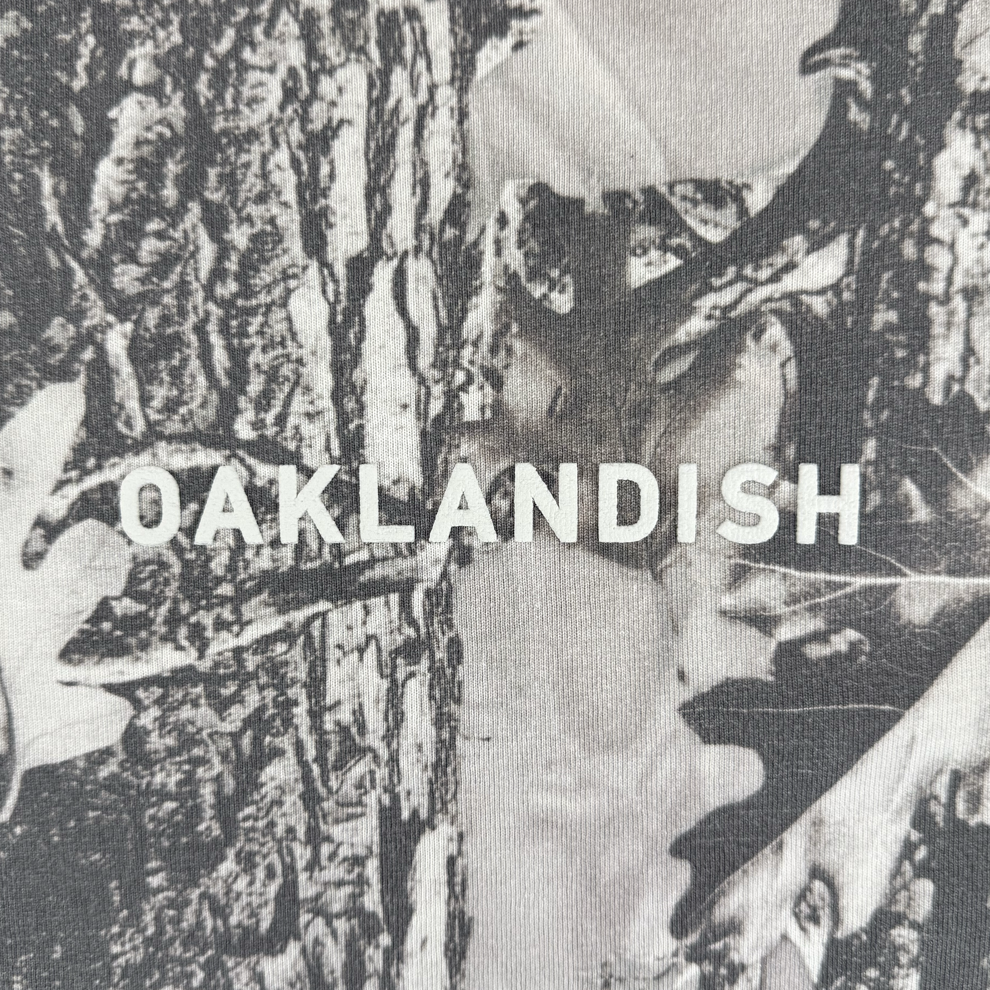 Close-up of heavyweight cotton fabric printed with the Oaklandish Classic Logo in bold, white uppercase letters centered against a textured background on this oversized tee by Oaklandish.