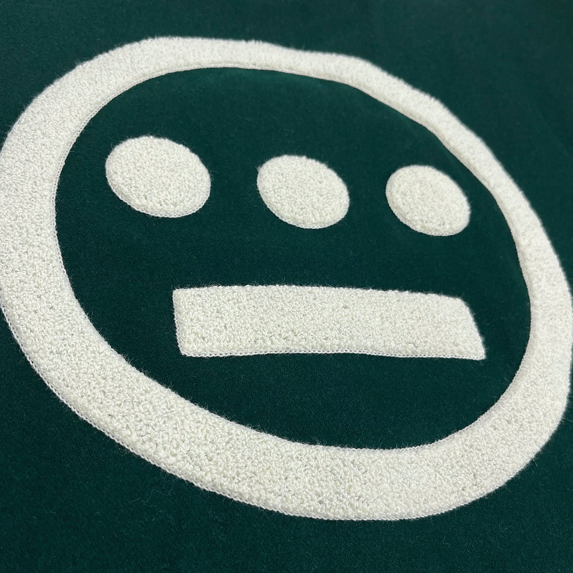 Side view close-up of a large white 3D Hieroglyphics hip-hop logo on the center back of a green varsity jacket.