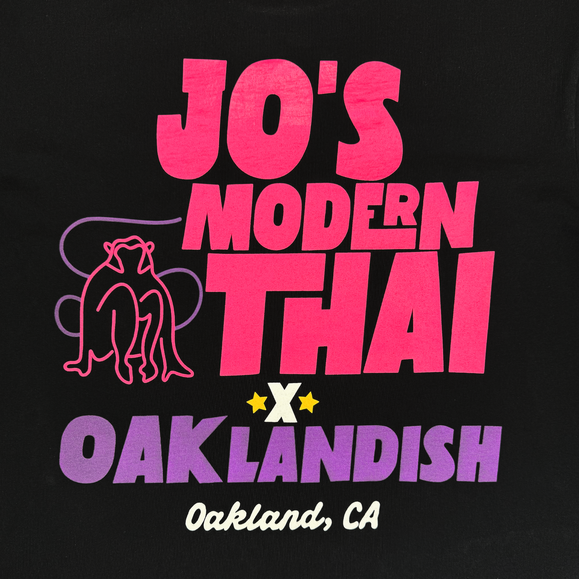 The Jo's Modern Thai X Oaklandish Tee by Oaklandish features "JO'S MODERN THAI x OAKLANDISH Oakland, CA" in pink, red, and purple on black with a minimalist cat above "THAI" and two yellow stars. Classic fit t-shirt style.