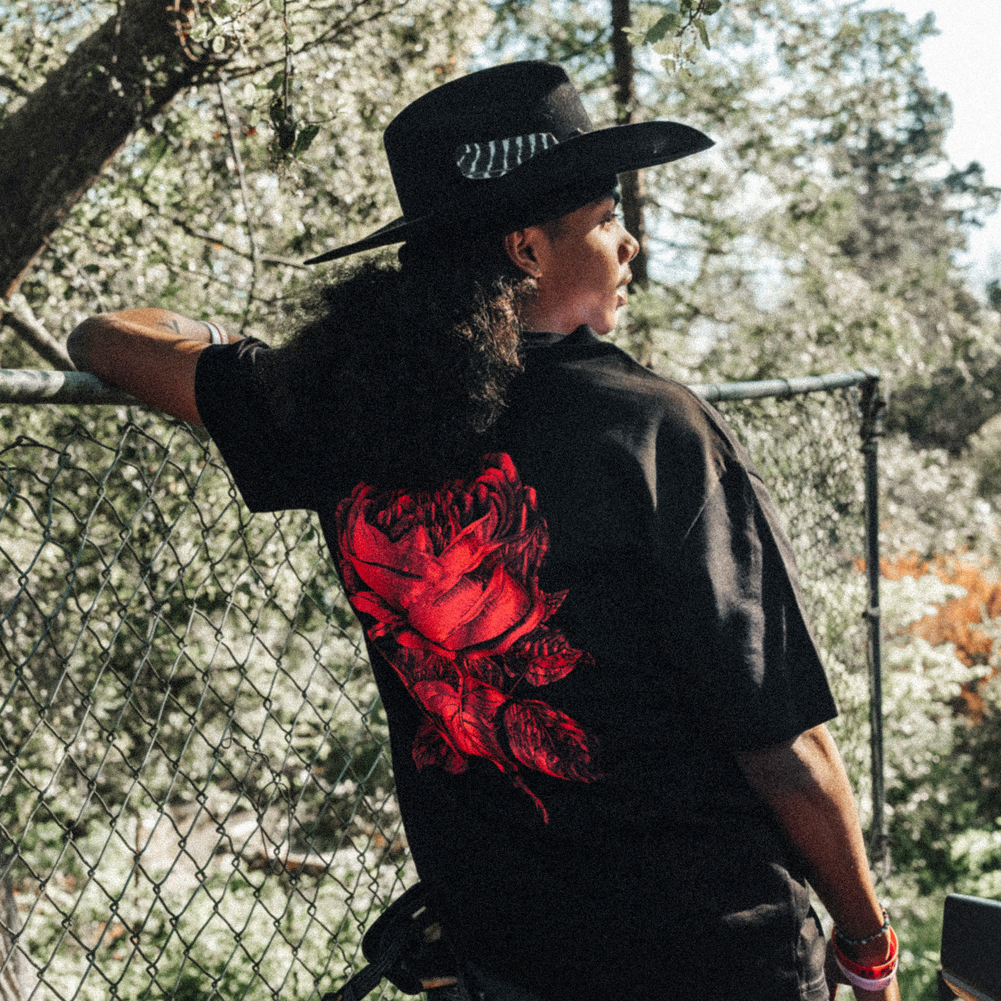 Back view of model wearing Black tee with red rose printed center.