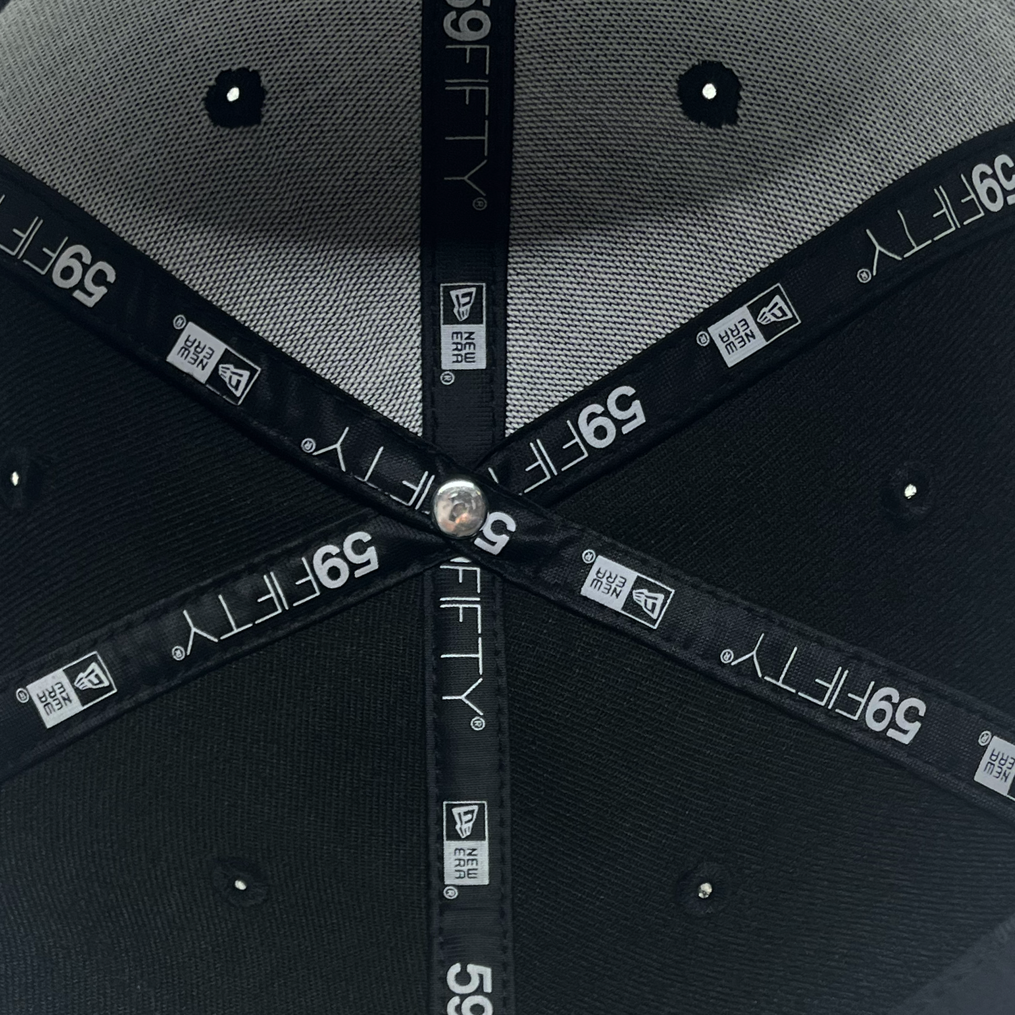 The underside of a New Era Pericos ALT 59FIFTY cap from Retail Vendors is shown, displaying its stitched panels and internal labels. The labels feature New Era branding, size information, and quality control tags. The cap's interior is structured with black lining and a central button where the panels converge.