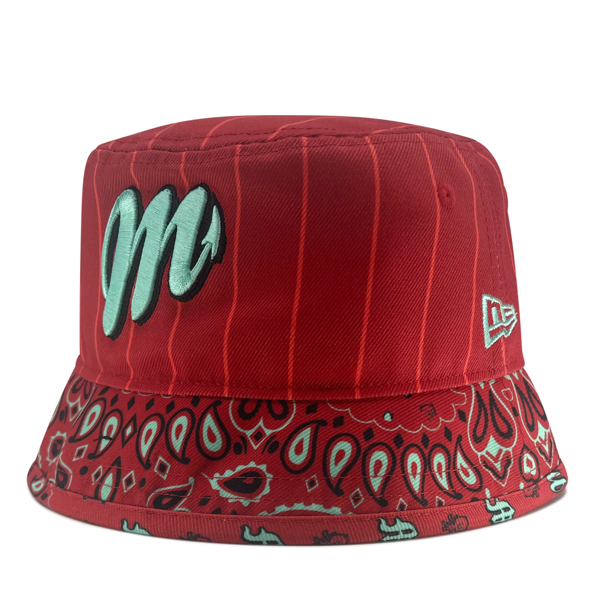 Introducing the New Era Diablos Paisley Bucket from Retail Vendors: a stylish red polyester bucket hat with an eye-catching light blue embroidered "M" on the front. The top half boasts a subtle striped pattern, while the brim features an elegant paisley design in light blue and black. Additionally, a white New Era logo is embroidered on the side for added flair.