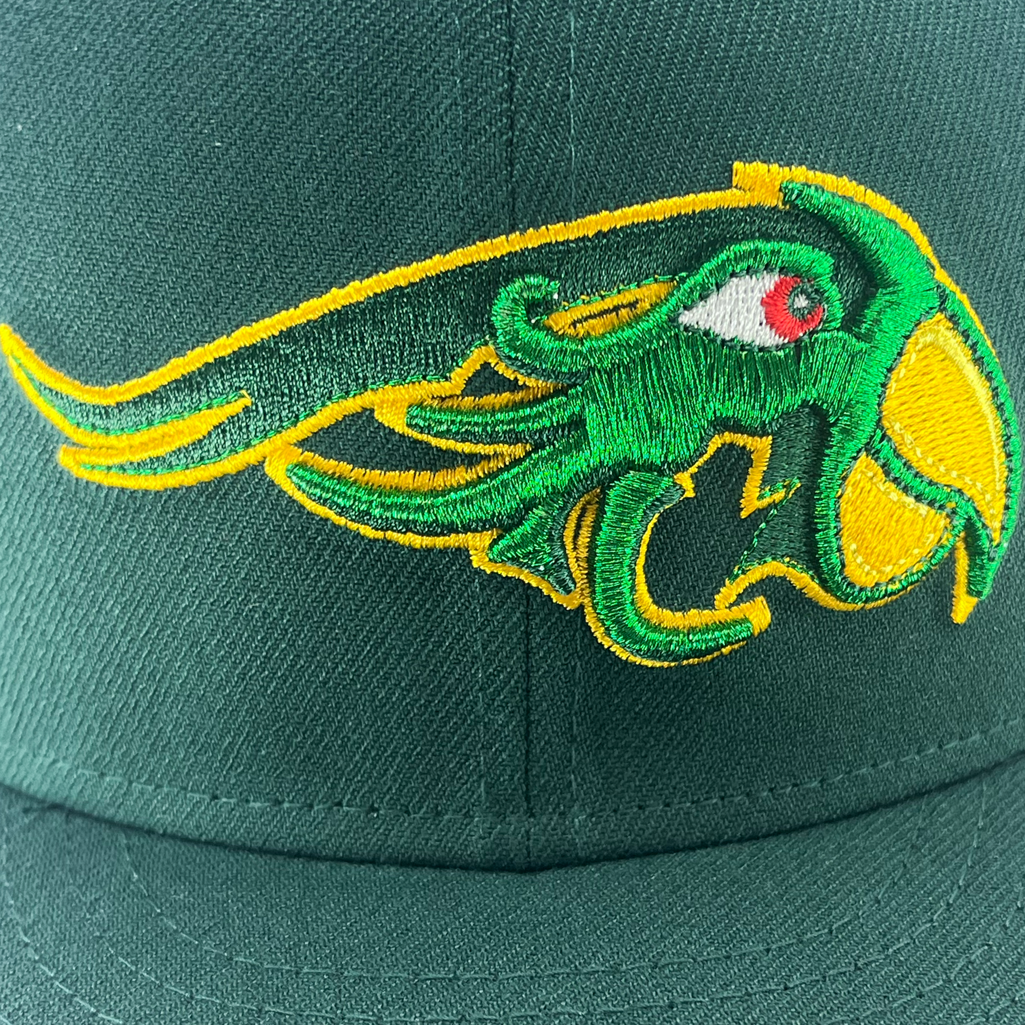 The New Era Pericos 59FIFTY Cap from Retail Vendors features a green baseball cap adorned with an embroidered mascot on the front. The stylized bird has a green body, yellow beak and highlights, and a red eye. The design is outlined in yellow with flowing lines that give it a dynamic and energetic appearance.
