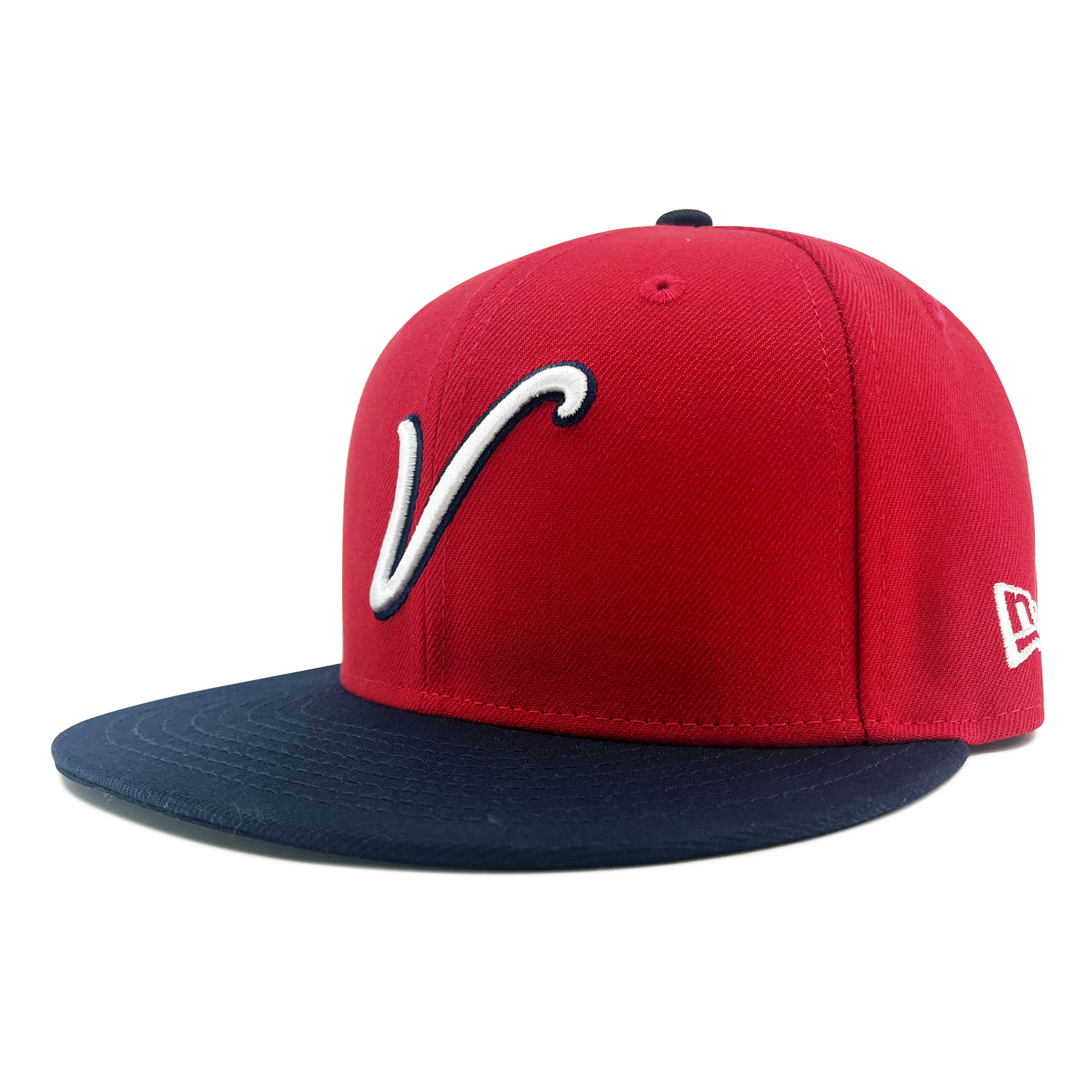 The New Era El Aguila Alt 59FIFTY Cap by Retail Vendors features a red design with a black brim. The front showcases a white, stylized letter "V" outlined in black. The side has a white embroidered logo with the letters "NE" in a stylized font, signifying its authenticity as an official New Era cap. This 59FIFTY fitted model comes with a structured, flat-brim design.