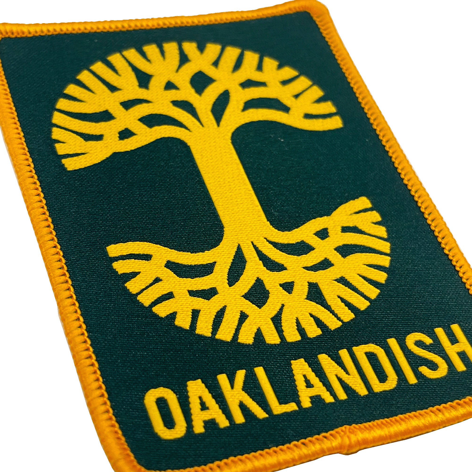The Oaklandish Rectangle Patch by Oaklandish features a rectangular, embroidered design with a stylized yellow tree with roots at its center against a dark green background. The word "OAKLANDISH" is written in yellow capital letters below the tree. This patch, perfect for accessories, is bordered by yellow stitching and exudes Oakland pride.