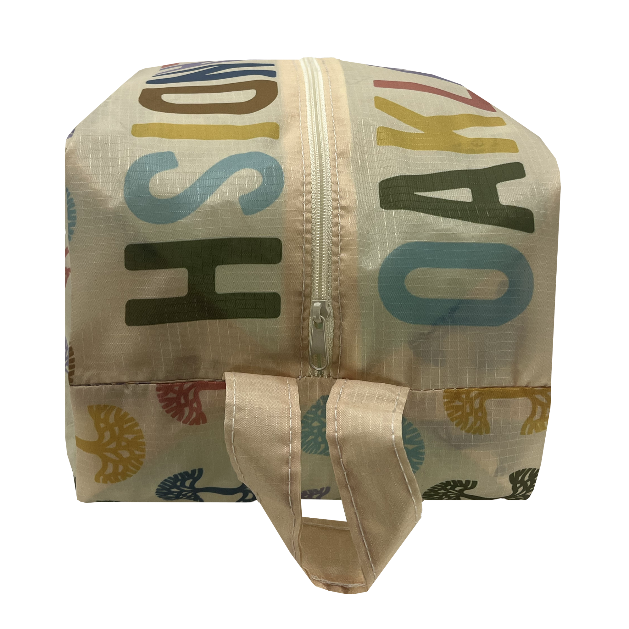 A close-up view of the Oaklandish Repeat Tree Pouch Large - Natural reveals a light-colored fabric bag equipped with a zipper. The bag showcases multi-colored, overlapping text featuring various letters and abstract tree designs. Made from durable ripstop material, it conveniently collapses flat for easy storage and includes a fabric loop handle at the top near the zipper.