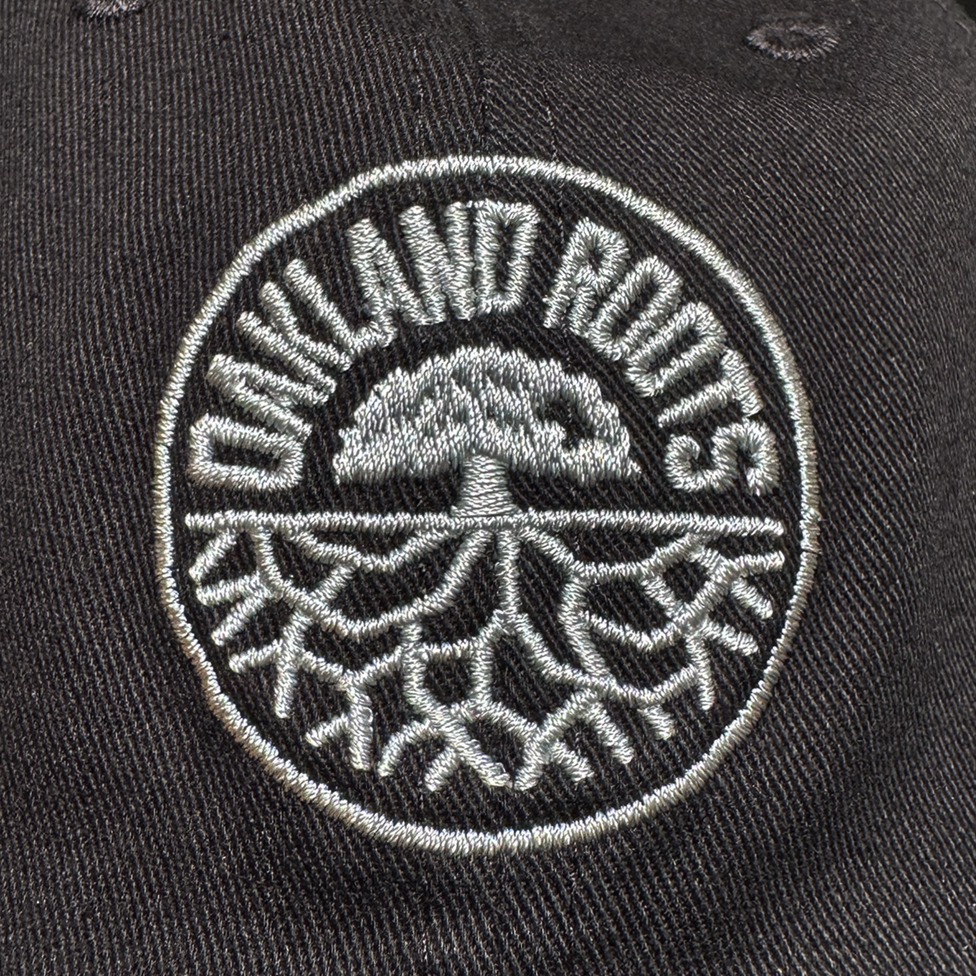 Close-up of a black ORSC Dad Hat by Oakland Roots SC, showcasing an embroidered circular tree and roots logo with "OAKLAND ROOTS" curved above in white—ideal for any Oakland Roots SC supporter.