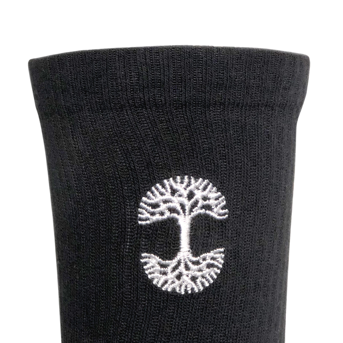 Close-up image of a pair of Oaklandish Embroidered Logo Socks in adult sizes, featuring a white embroidered design near the top. The design showcases a tree with roots in a circular formation, symbolizing growth and stability. The texture of the ribbed knit fabric is clearly visible against a plain white background.
