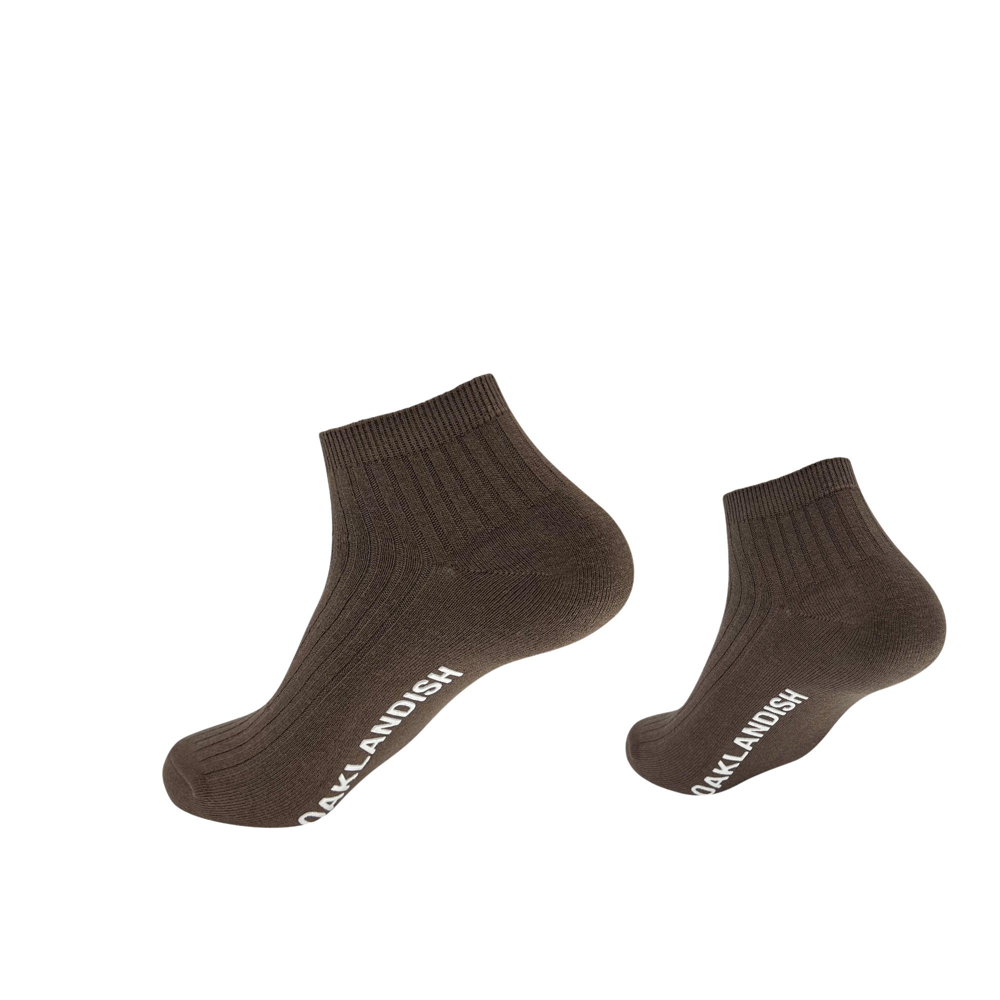Two dark brown, cotton Grip Low Crew Socks by Oaklandish with a ribbed texture are displayed against a plain white background. The socks feature the text "OAKLANDISH" in white lettering along their sides. The image shows one sock elevated and slightly angled, while the other is positioned upright.