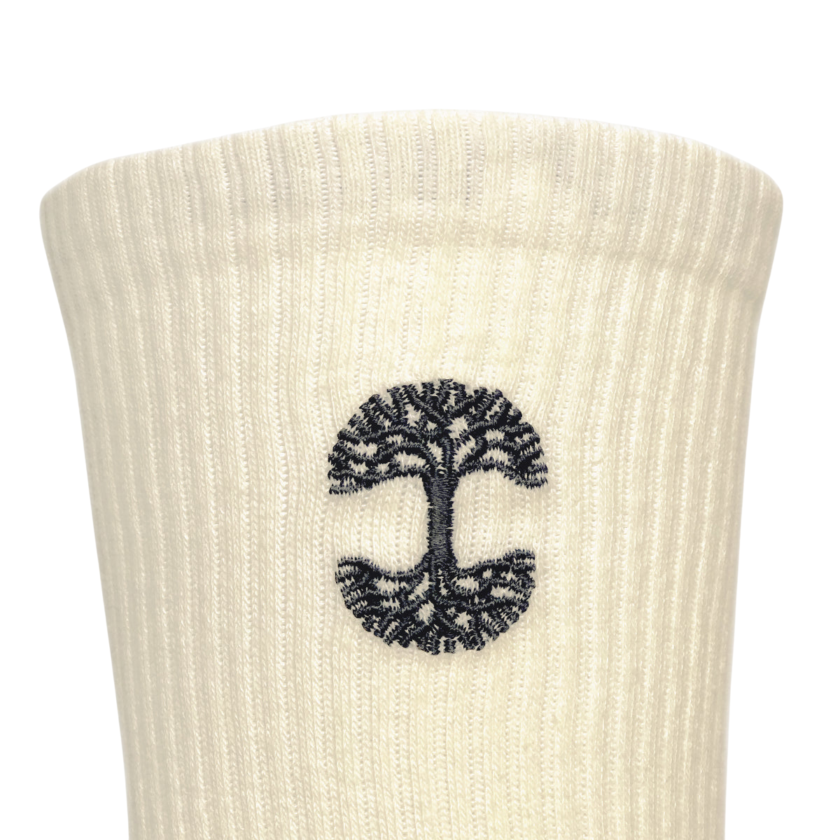 Close-up of the white ribbed fabric from the Oaklandish Embroidered Logo Socks, featuring a black tree of life design. The symmetrically spread roots and branches are enclosed within a circular border, centered on the socks, showcasing the iconic Oaklandish style.