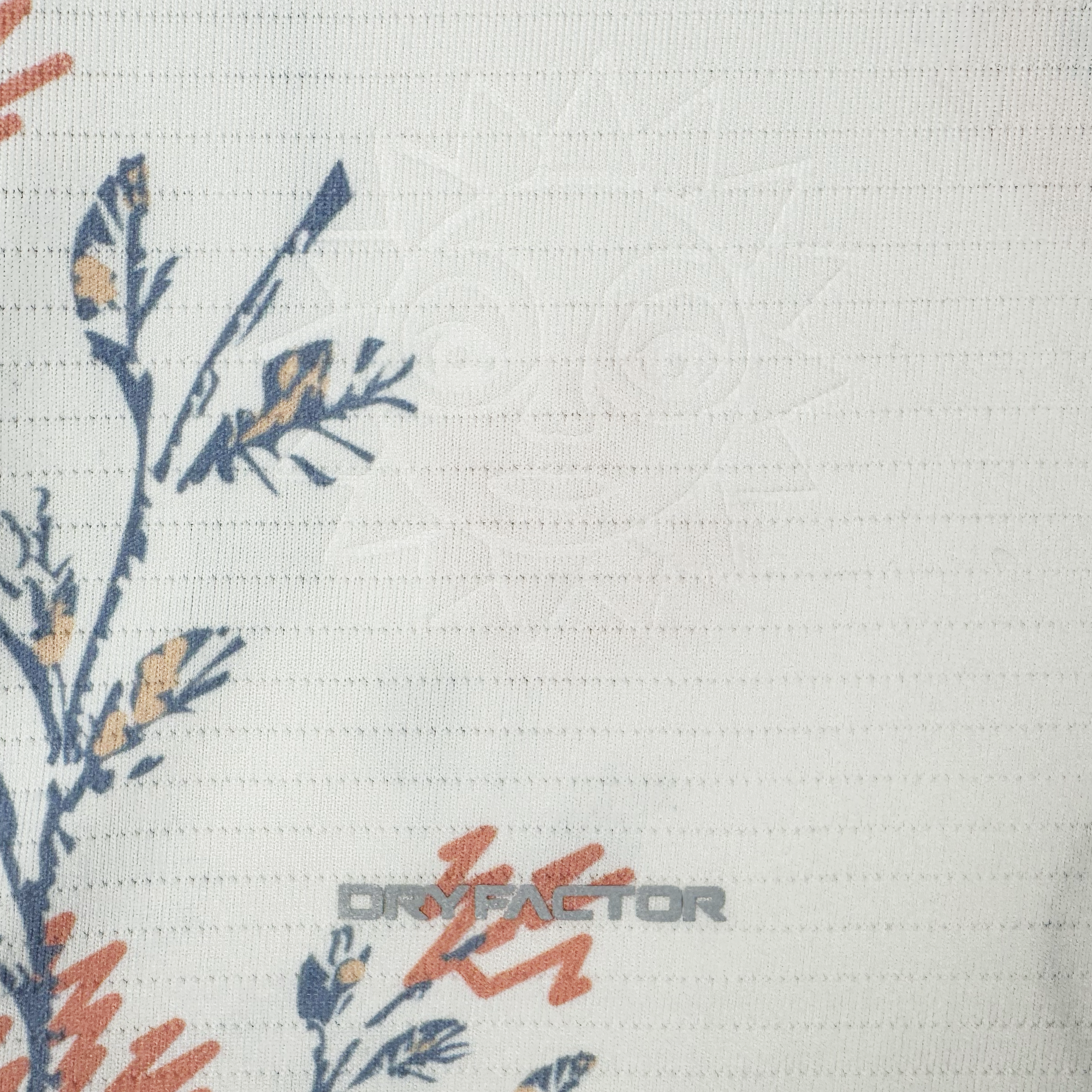 A close-up of the white Custom 2026 OAKLAND SOUL SC FORM JERSEY by Oakland Soul shows a subtle embossed sun face, blue and orange florals on the left, "DRYFACTOR" near the bottom, and a fine waffle-like texture on this custom name jersey.