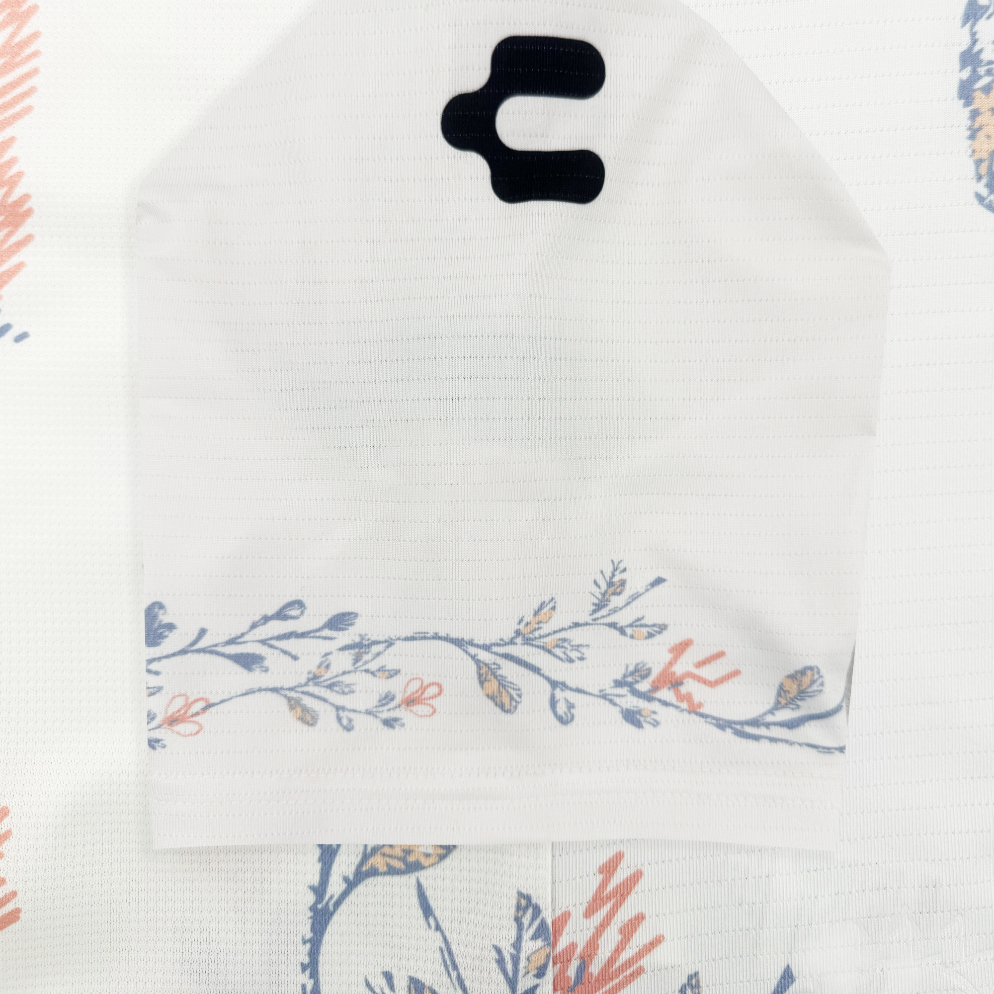 The white Oakland Soul 2026 FORM Jersey features a subtle grid texture and a curved floral design in blue, orange, and beige along the bottom edge. Two black cutouts near the top right provide ventilation. The background shows a matching floral pattern.
