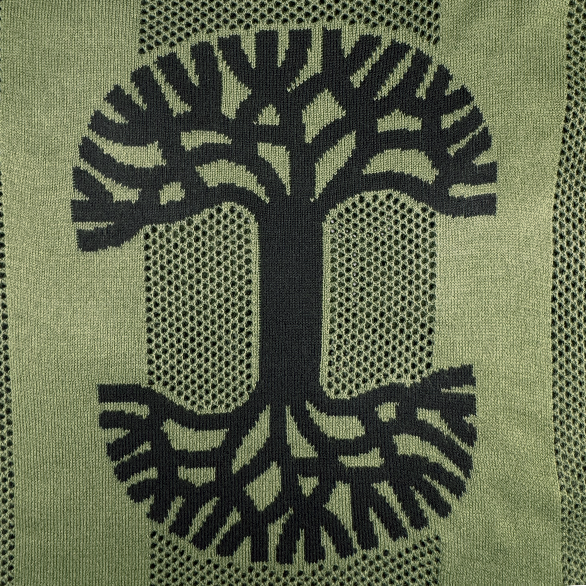 A black tree forms a “C” on the green, textured knit of the Oaklandish Terrace Sweater by Oaklandish. Intricate branches and roots fill the letter, while mesh-like fabric adds depth, echoing an army-inspired look.