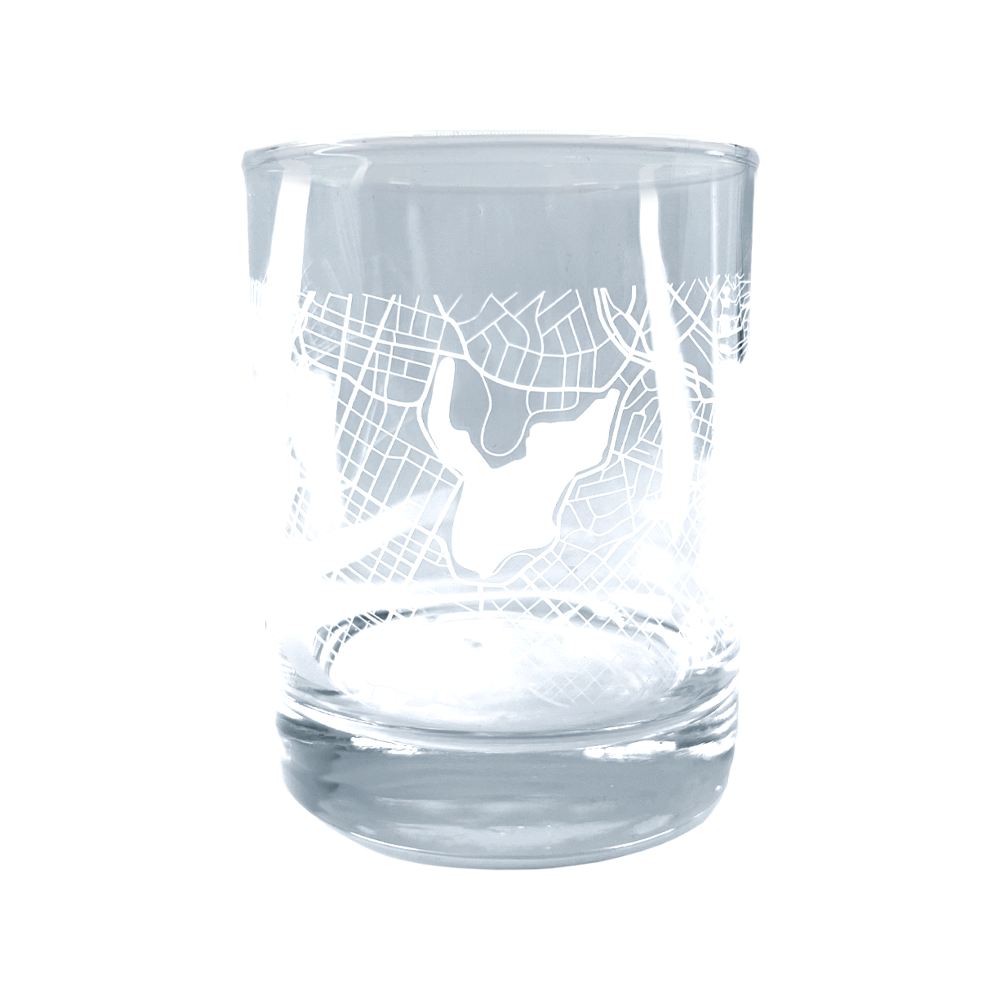 Introducing the Oaklandish Aerial Tumbler, a clear whiskey glass adorned with an intricate etched design that mirrors an aerial map of Oakland. Featuring distinctive lines and a central shape that could indicate a lake or landmark, this classic tumbler boasts a thick base and smooth, cylindrical contour.