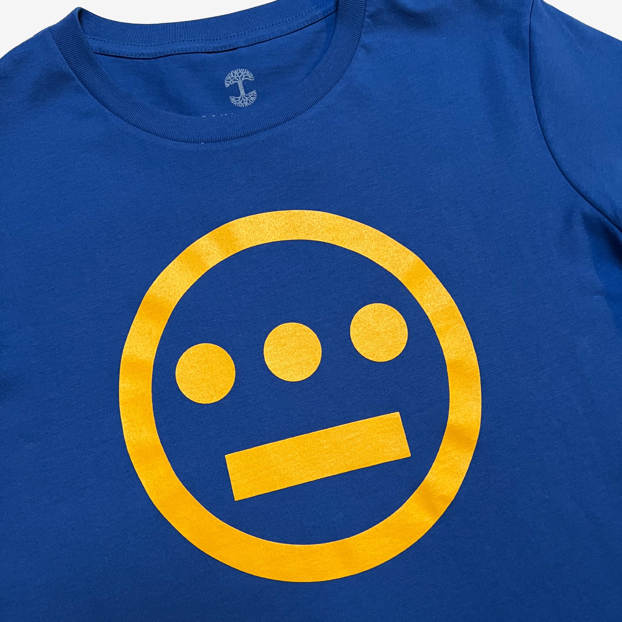 Close up of yellow Hieroglyphics Hip-Hop logo on a royal blue t-shirt.