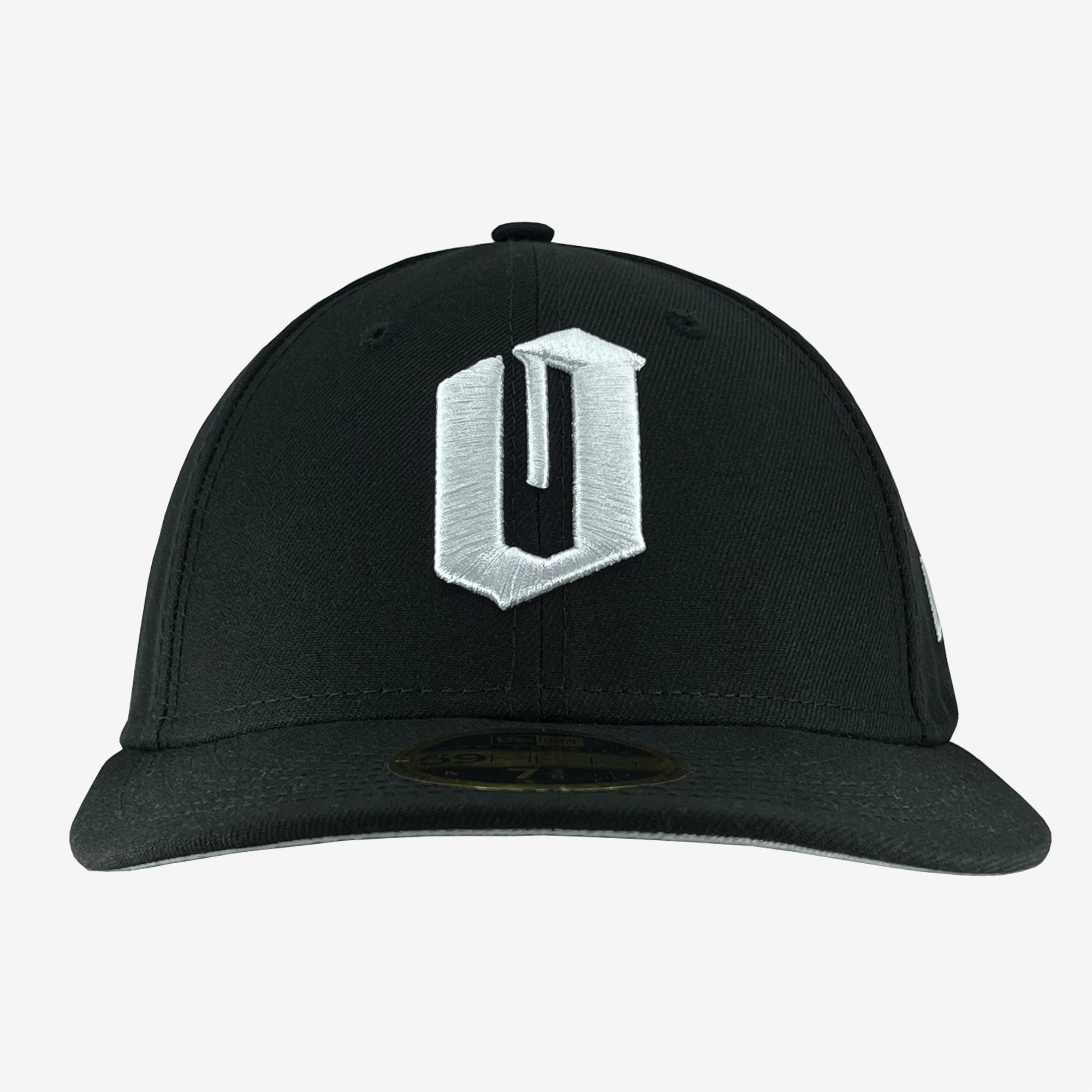 A black New Era Official Low Profile 59FIFTY Fitted Cap by Oaklandish, with a prominent white letter "U" embroidered on the front panel. This cap features a flat brim and includes a sticker visible on the underside of the brim. The background is plain white.