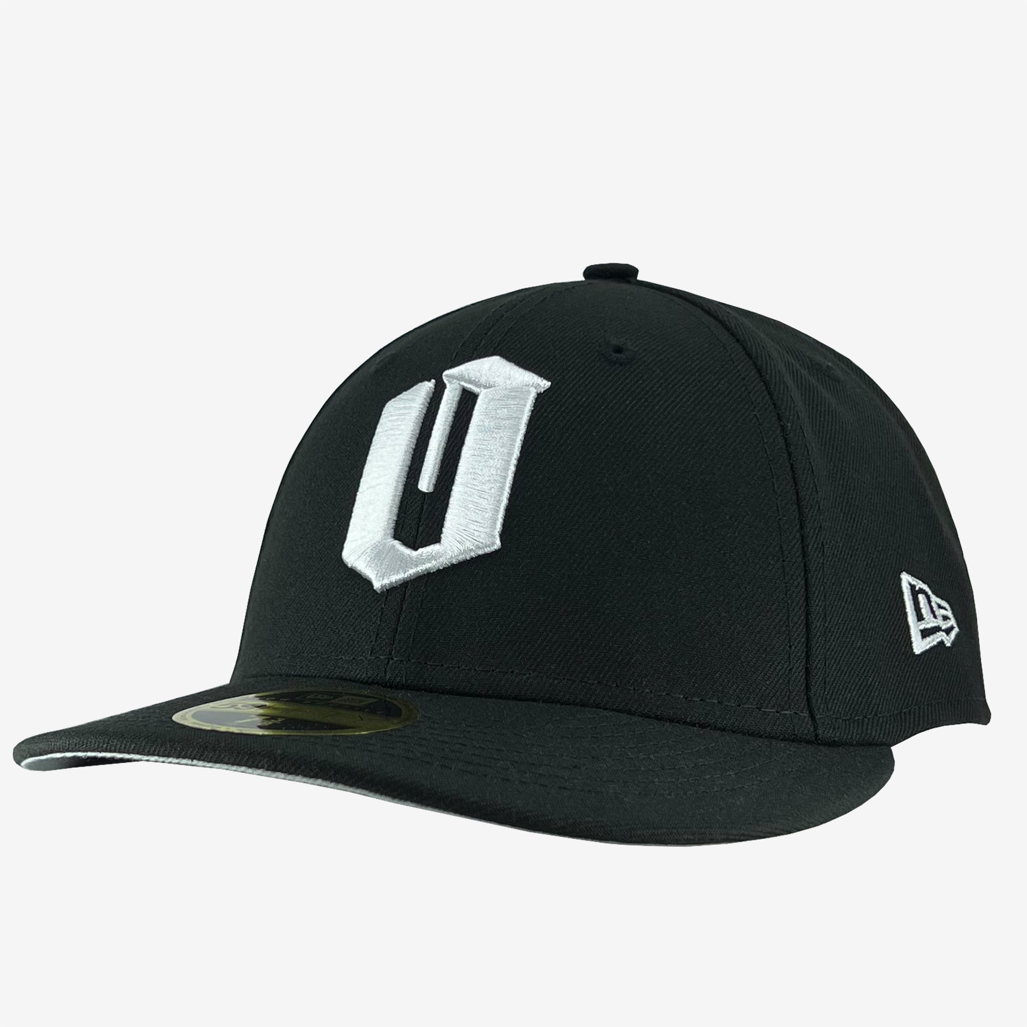 A black Oaklandish New Era Official Low Profile 59FIFTY Fitted Cap featuring a bold, white "U" logo on the front. The cap has a flat brim with a gold sticker on the top and the New Era logo in white on the right side. It is set against a plain white background.