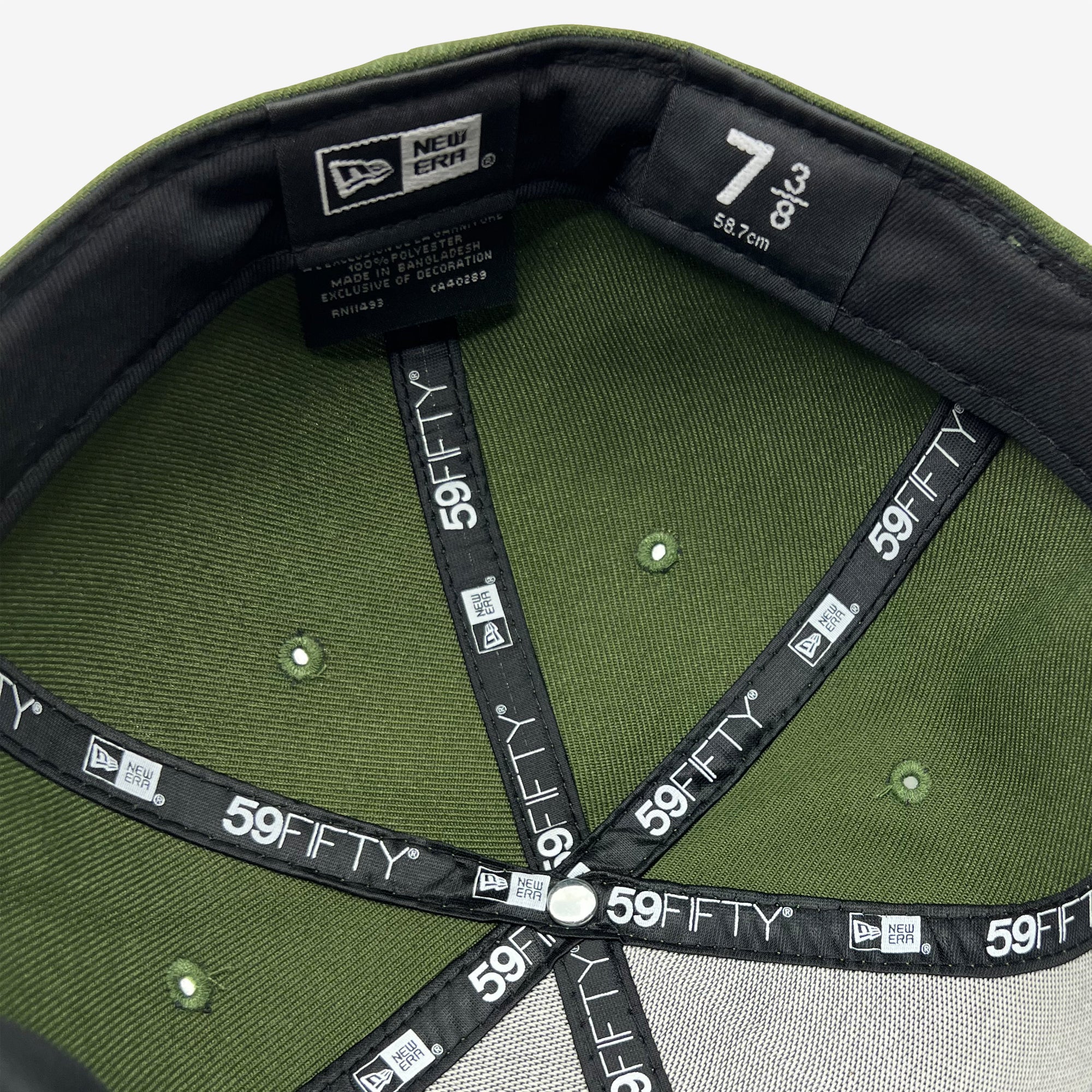 Interior view of a green New Era Official 59FIFTY Fitted Cap, showing the inside of the crown and the black sweatband. The sweatband is labeled "New Era 59FIFTY," with the size "7" (56.7 cm) on its center label. The interior features black cross-stitching, creating six segments, with Oaklandish brand labels sewn around the interior.