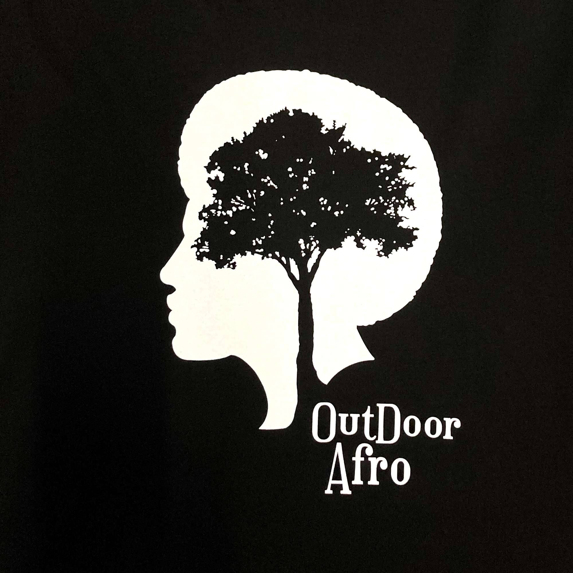 The Outdoor Afro Hoodie by Partner features a design showing the silhouette of a person's head in profile with a tree forming the shape of their hair. The design is rendered in white on a black background, and "Outdoor Afro" is written in stylized white text at the bottom right, making it perfect for this premium heavyweight fleece pullover hoodie.