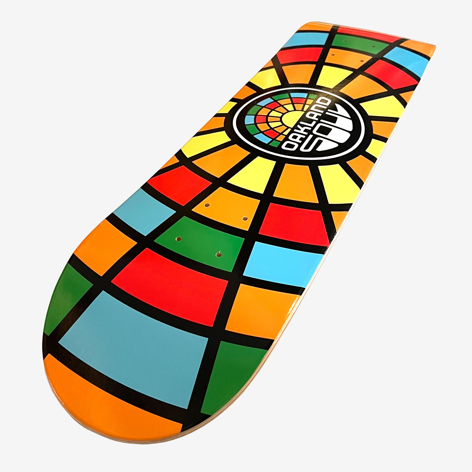 The Oakland Soul Logo Skate Deck by Oakland Soul features a 7-ply maple wood construction with a vibrant geometric design set against a white background. The pattern of orange, blue, red, and yellow squares and rectangles converges at a central circular logo that reads "OAKLAND SOUL SC.