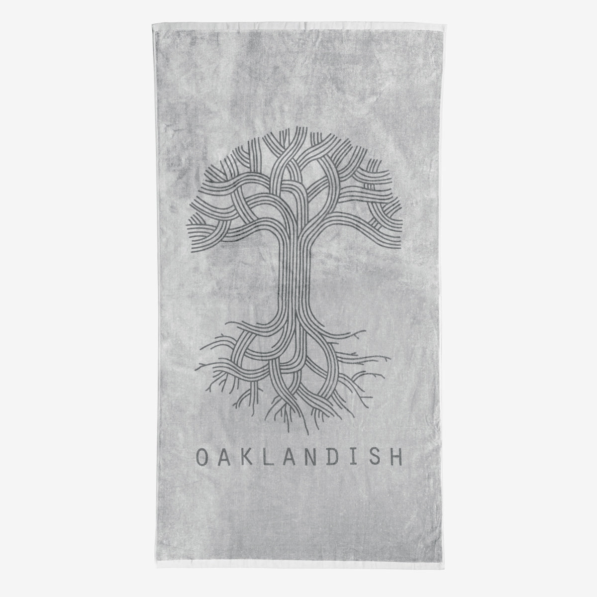 The Classic Logo Beach Towel by Oaklandish is a grey, oversized towel featuring an intricate, stylized tree design with numerous curved branches and roots in the center. Below the tree, "OAKLANDISH" is prominently displayed in capital letters. Made from 100% ringspun cotton, this super soft towel features a lighter grey background.