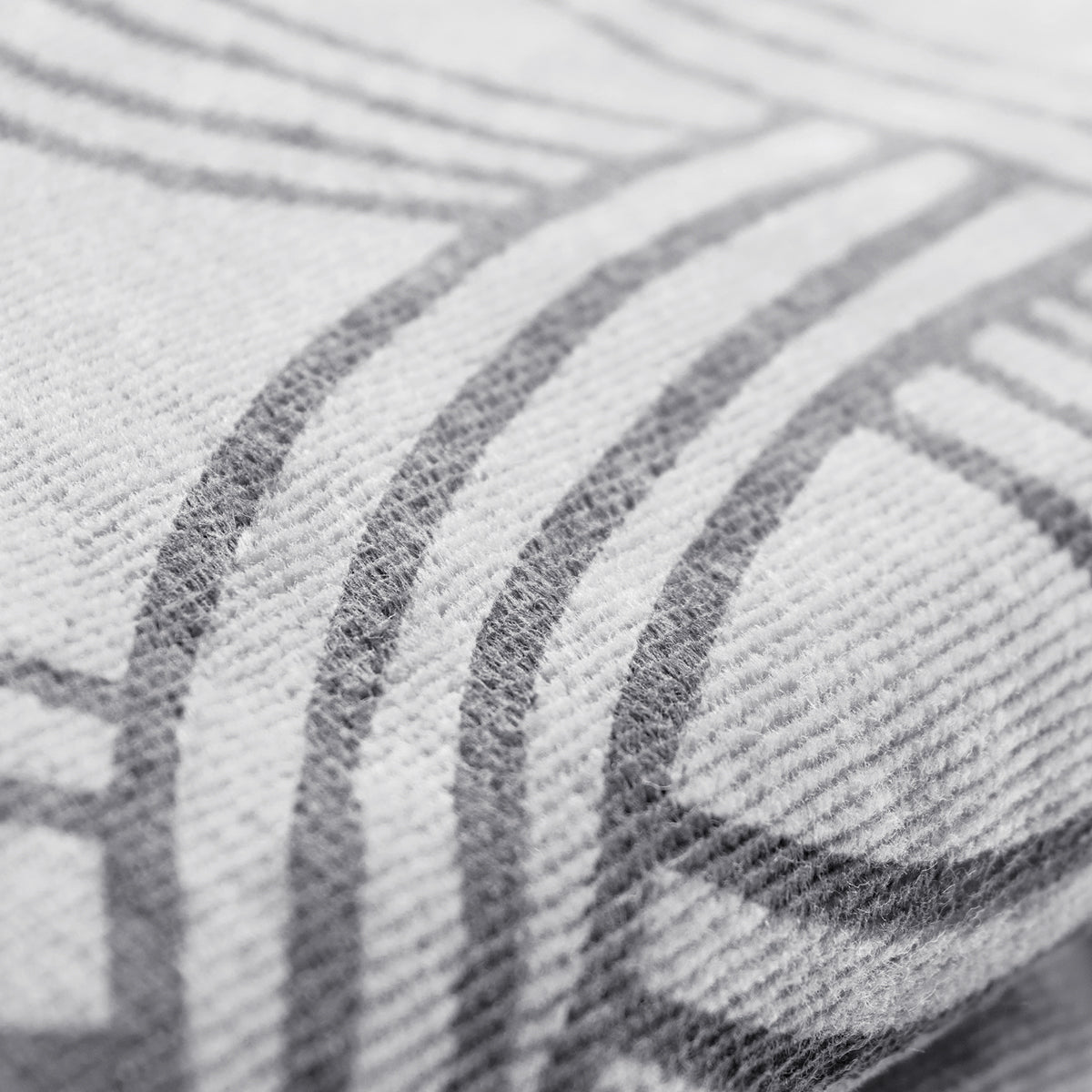 A close-up image of the Classic Logo Beach Towel by Oaklandish features a pattern with intersecting geometric lines. Made from 100% ringspun cotton, the super soft fabric appears textured, with visible fibers creating a slightly raised surface. The lines are gray against a lighter gray background, giving a monochromatic look.