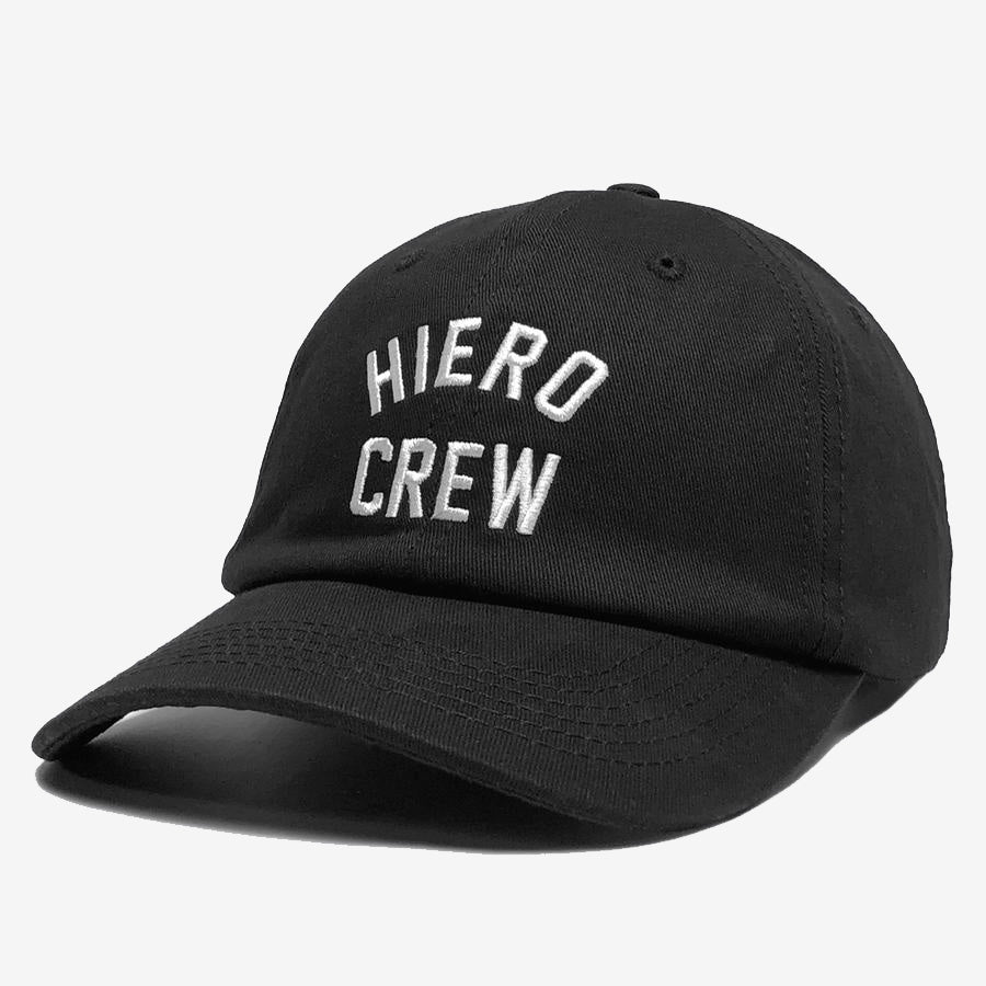 The Hiero Crew Dad Hat by Hieroglyphics features black fabric with white embroidery spelling "HIERO CREW" in uppercase letters on the front panel. This adjustable strapback has a curved brim and is showcased against a plain white background. The hat includes minor creases around the crown area, adding character to its casual style.