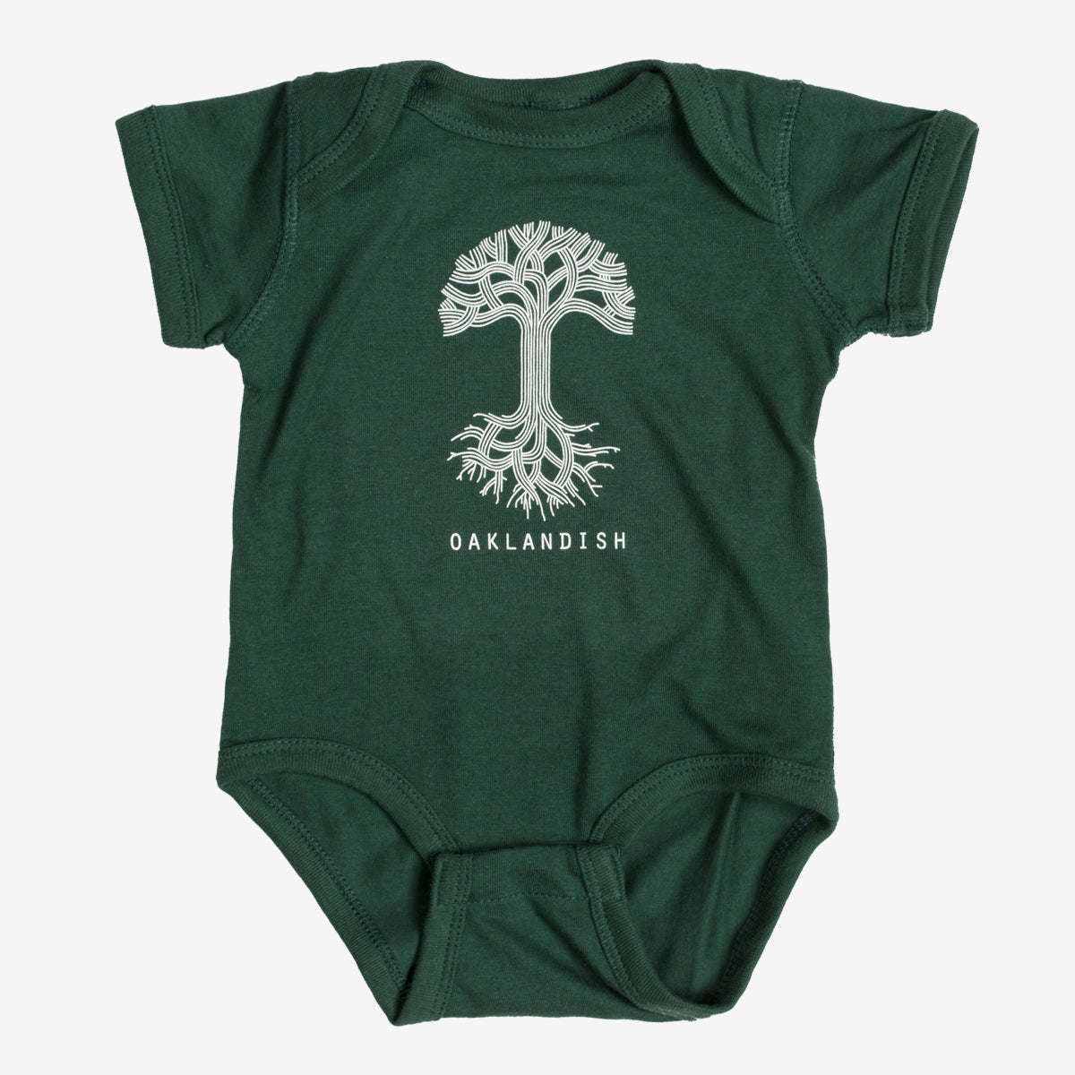 The Infant Oaklandish Classic Logo One-Piece by Oaklandish is a green baby romper showcasing a white, stylized tree with intricately designed roots and branches. Beneath the tree, "OAKLANDISH" is printed in bold, white capital letters. Crafted from soft ring-spun cotton, this short-sleeved one-piece features reinforced snap closures at the bottom for convenience.