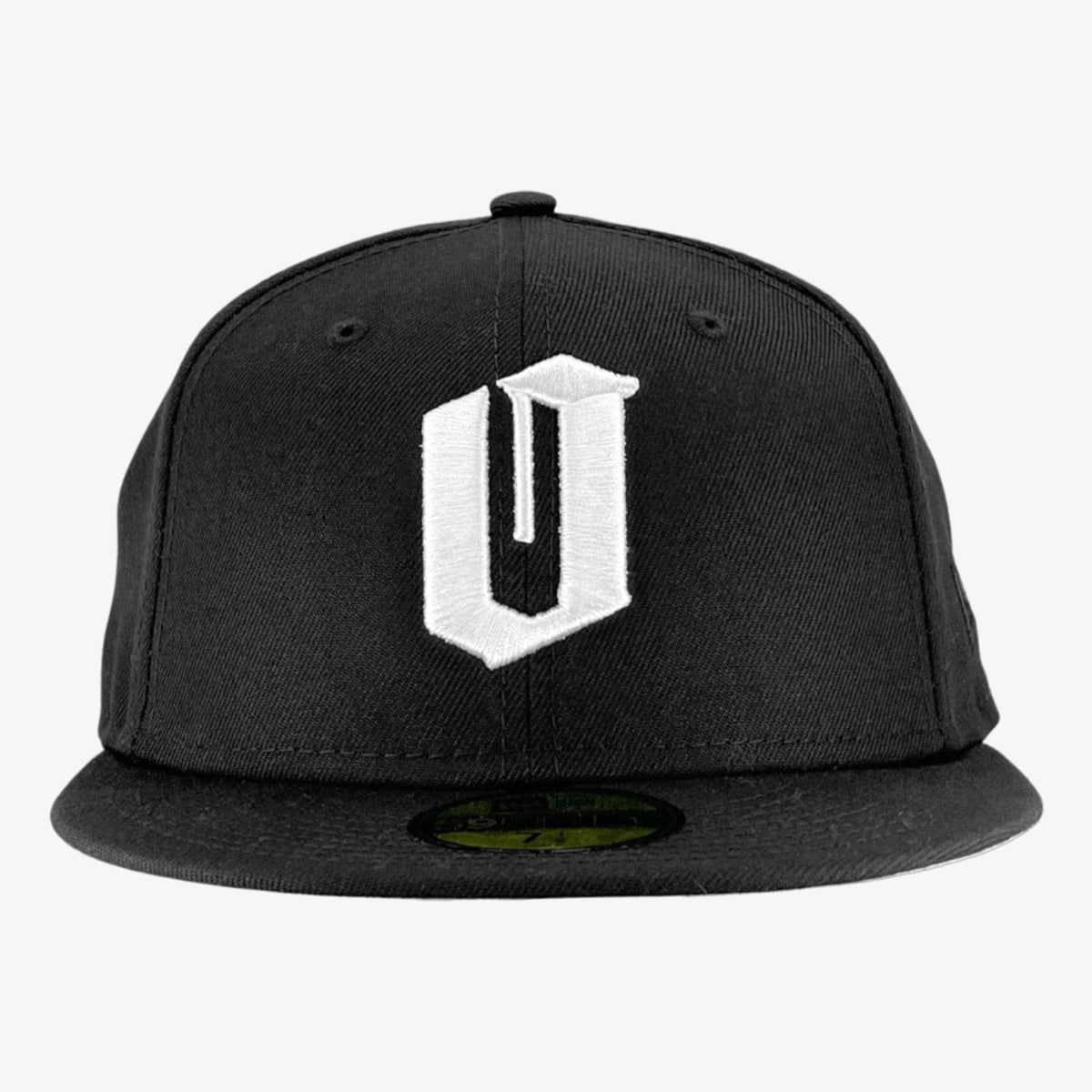 A New Era Official 59FIFTY Fitted Cap by Oaklandish, featuring a six-panel design with small ventilation holes on each panel and a button at the top. This black cap includes a stylized white letter "V" embroidered on the front center and has a green underside to its flat brim.