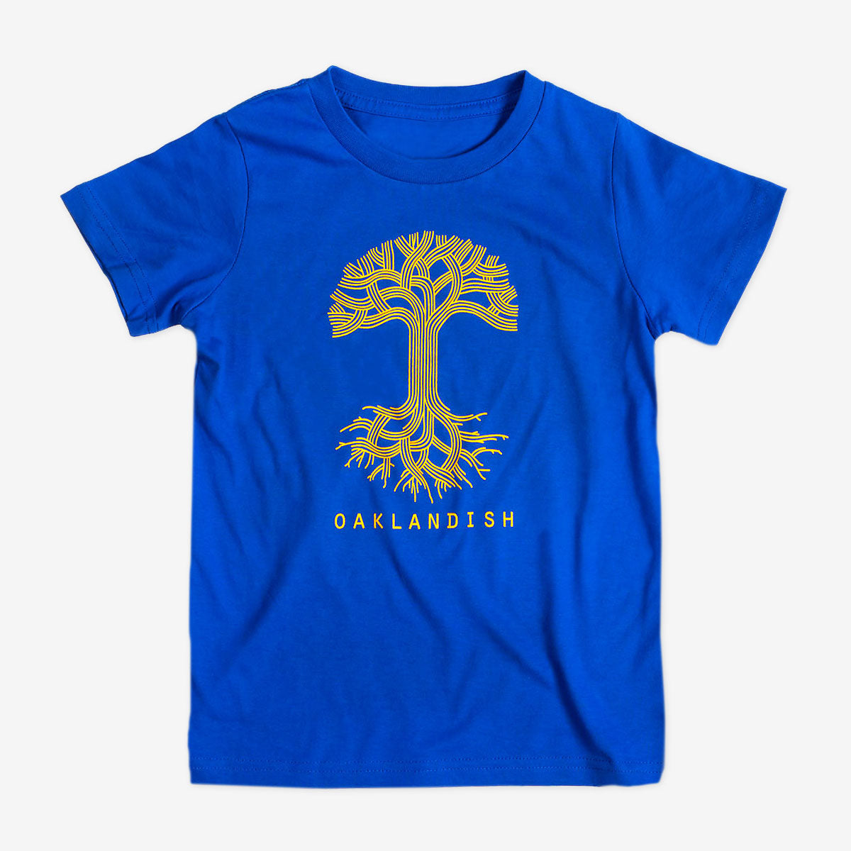 The Youth Oaklandish Classic Logo Tee by Oaklandish is a royal blue youth T-shirt made from 100% cotton. It features a stylized yellow tree design with intricate, symmetrical branches and roots extending from the center. Below the tree, the word "OAKLANDISH" is printed in bold capital letters.
