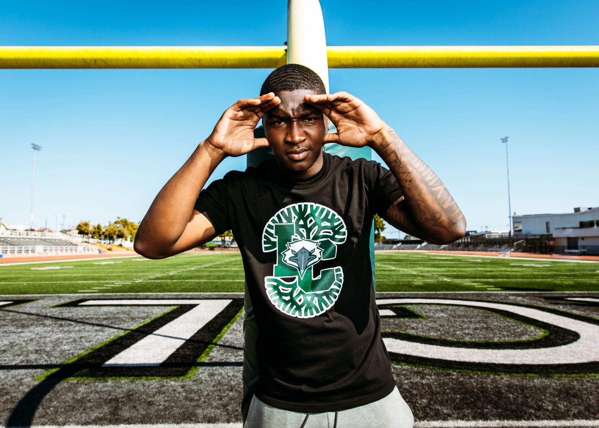 Guy in front of field goal wearing mashup design of Oaklandish tree and LC for Laney College and eagle mascot.