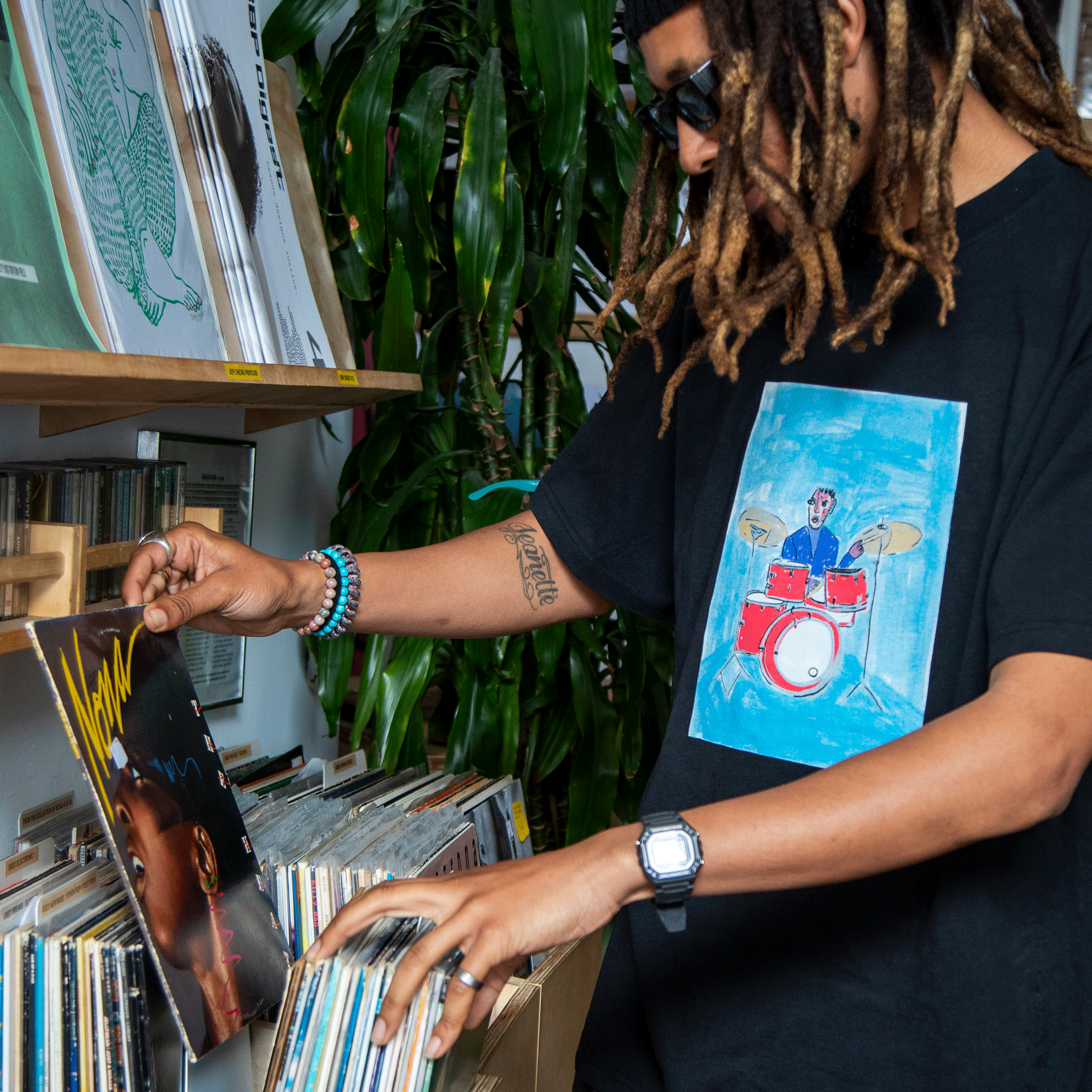 Person browsing through records in a store with plants in the background
