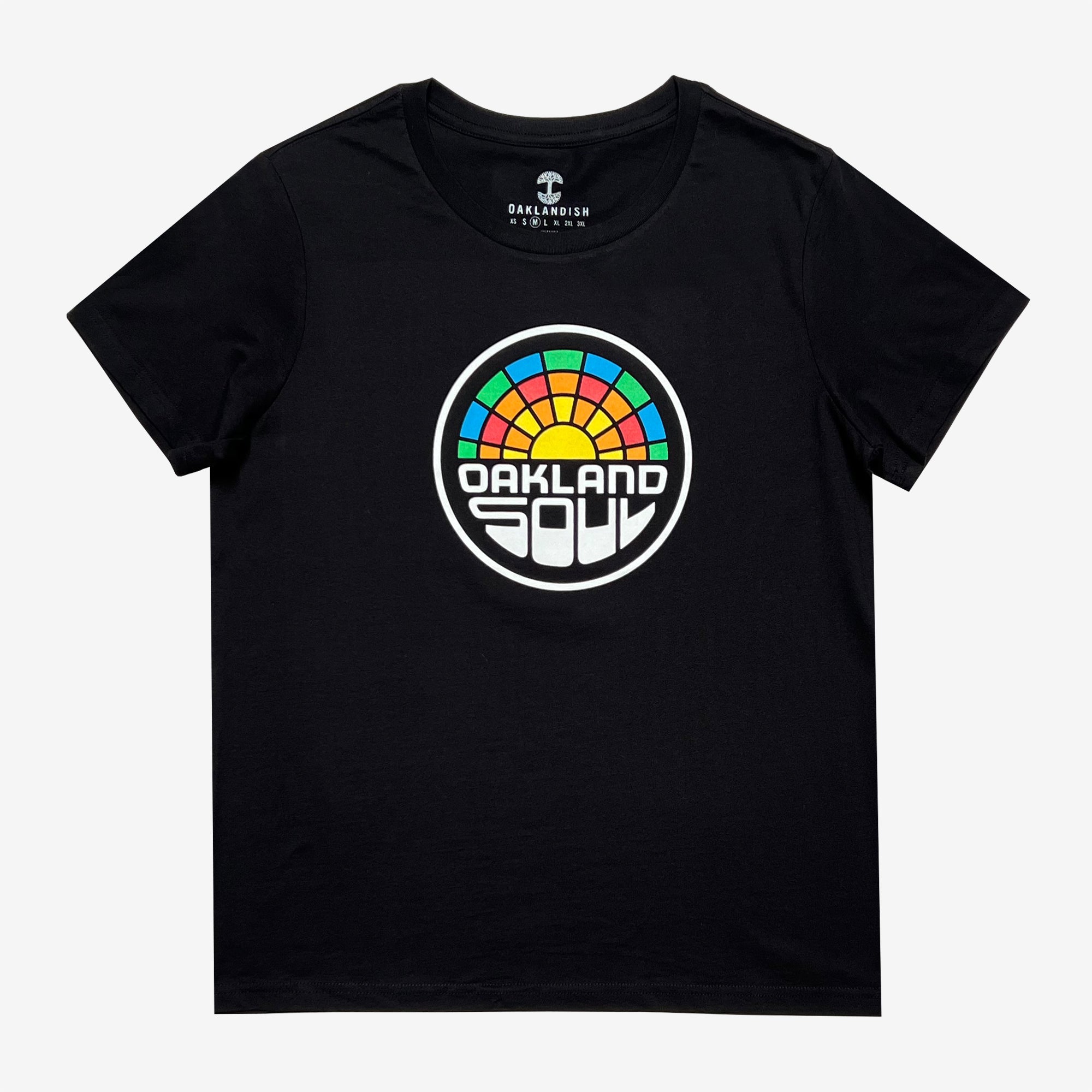 The Women's Oakland Soul Logo Tee by Oakland Roots SC is a black classic fit t-shirt showcasing a vibrant circular design at its center. The design includes the words "OAKLAND SOUL SC" in bold white text beneath an arc of multicolored segments that evoke a sunset. The shirt, available in women's sizes, is presented on a plain, light background.