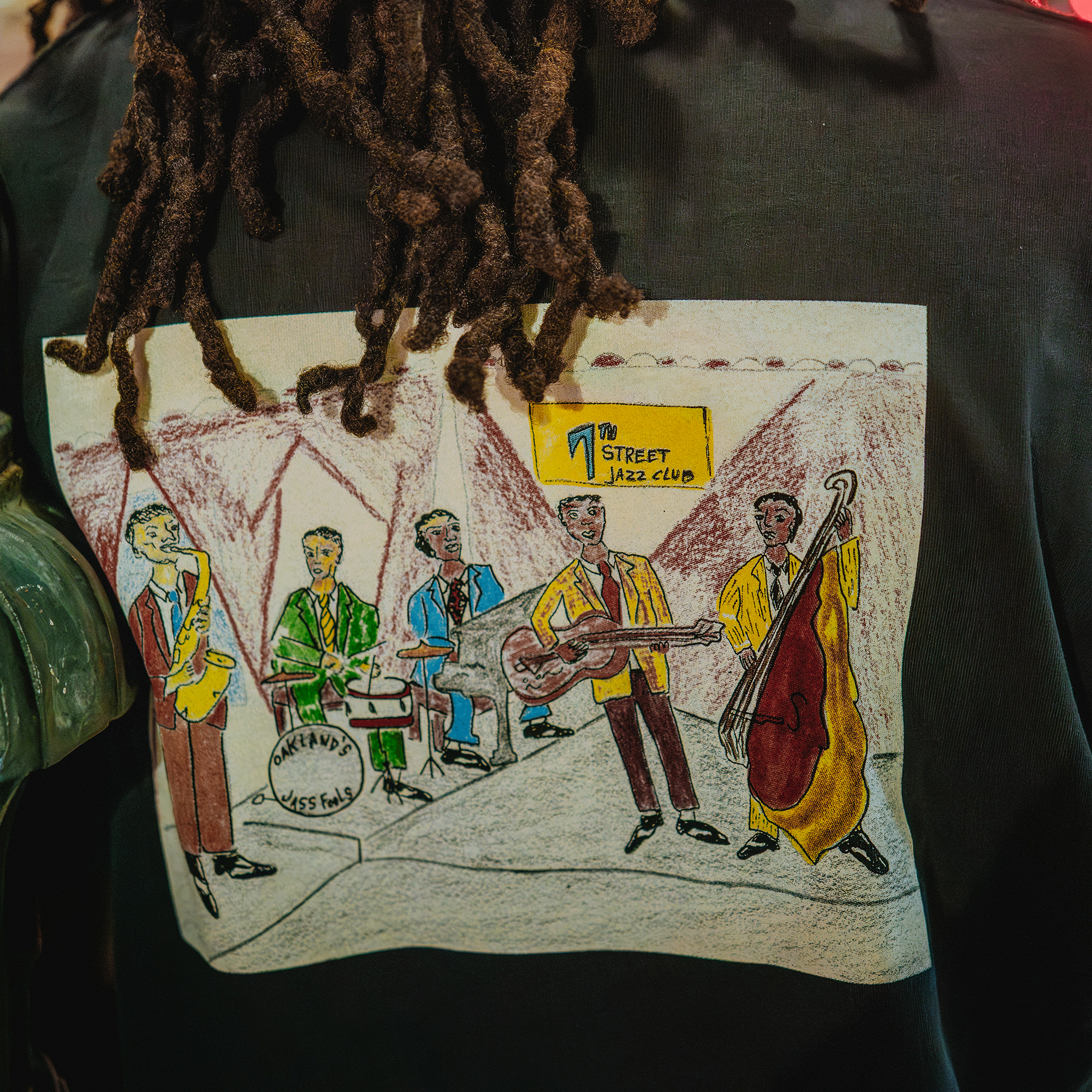 Person wearing a shirt with a hand-drawn illustration of a jazz band at the 7th Street Jazz Club.