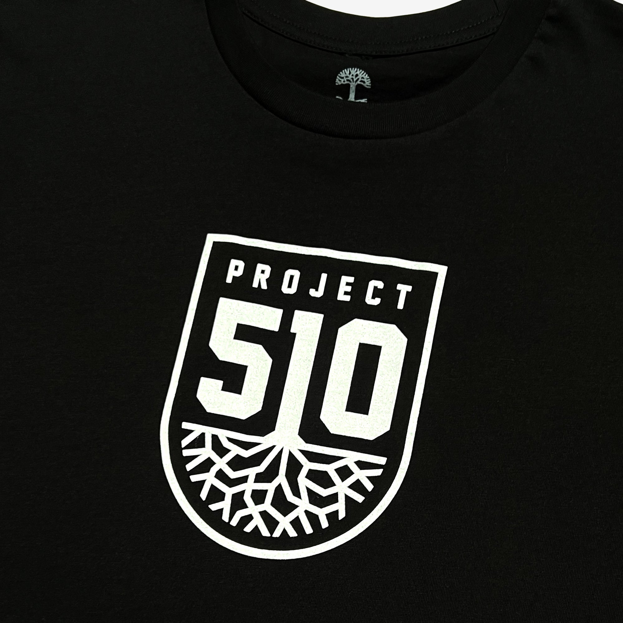 A black Project 510 Club Tee by Oakland Roots SC, featuring a white shield-shaped logo with "PROJECT 510" at the top and the number "510" above a stylized tree with spreading roots at the bottom, symbolizing their soccer club Project 51O.