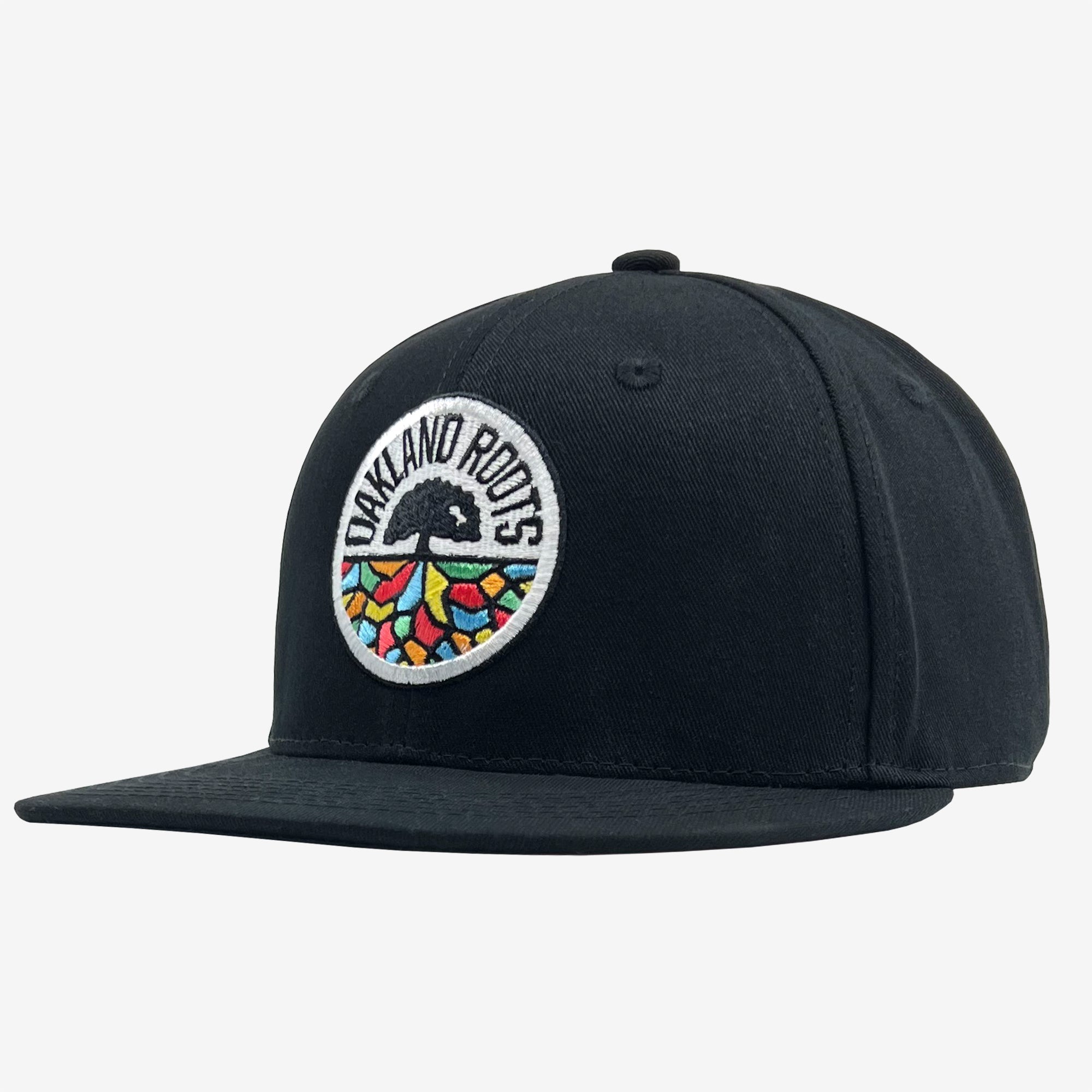 The Oakland Roots SC Structured Snapback is a black baseball cap showcasing the Oakland Roots logo on the front. The logo features a circular patch with "Oakland Roots" text at the top and a vibrant tree design at the bottom. This snapback, reflecting its Oaklandish heritage, includes a flat brim, six-panel construction, and a button on top.