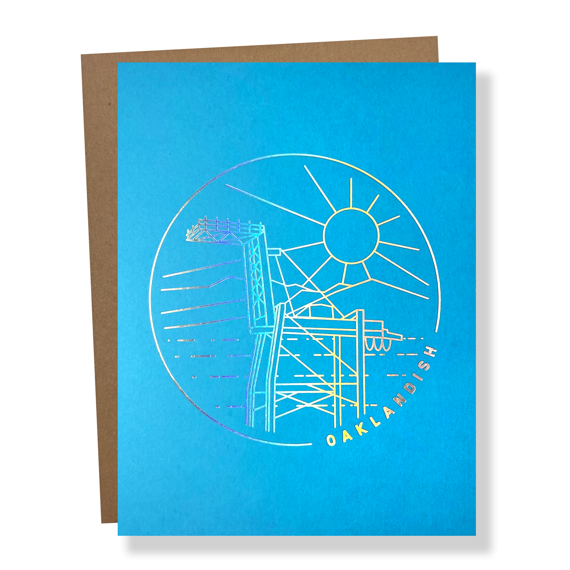 Blue greeting card with a circular gold line drawing of an Oakland crane and OAKLANDISH wordmark with a brown envelope.