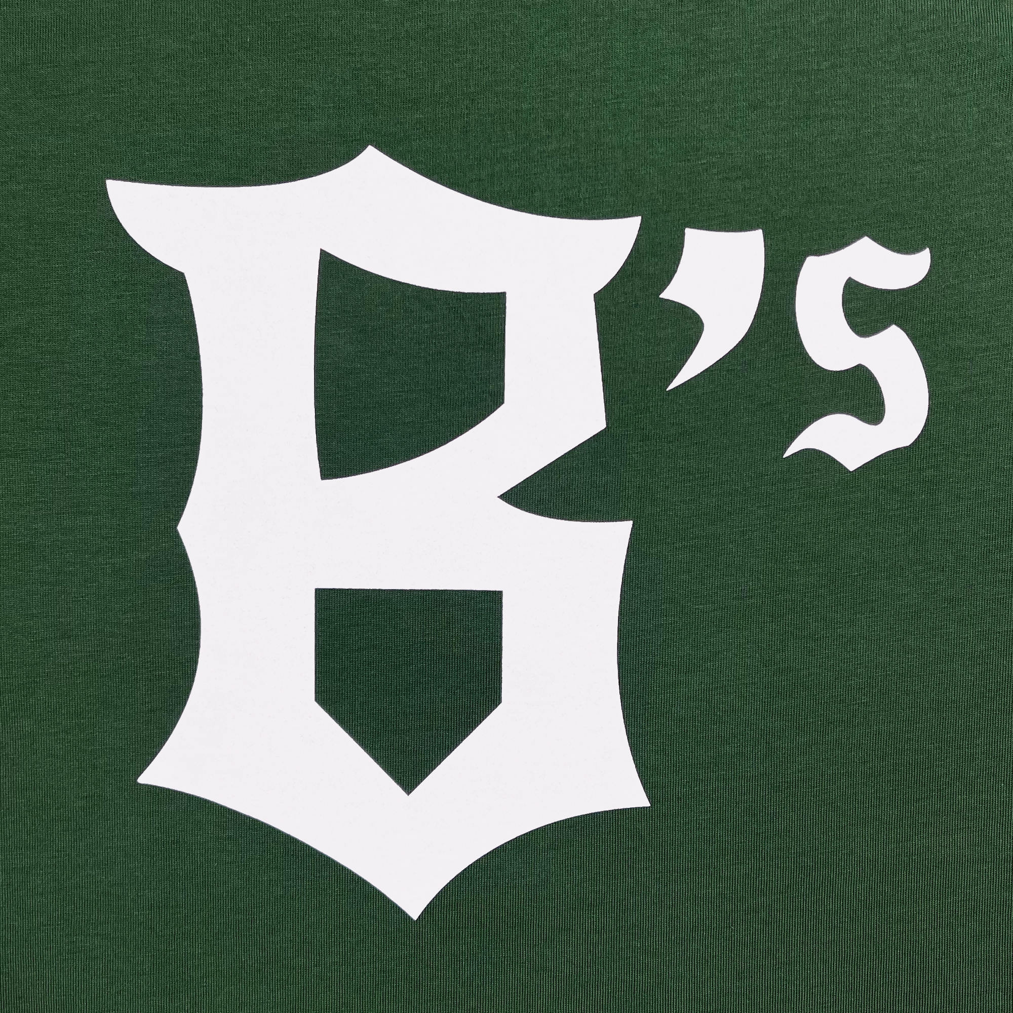 The Oakland Ballers B Logo Tee showcases a stylized graphic with a large, white Gothic-style letter "B" followed by a small 's' in a different Gothic font, all set against a solid green background. The design is reminiscent of the classic logos seen in the Pioneer League for professional baseball teams like the Oakland Ballers.