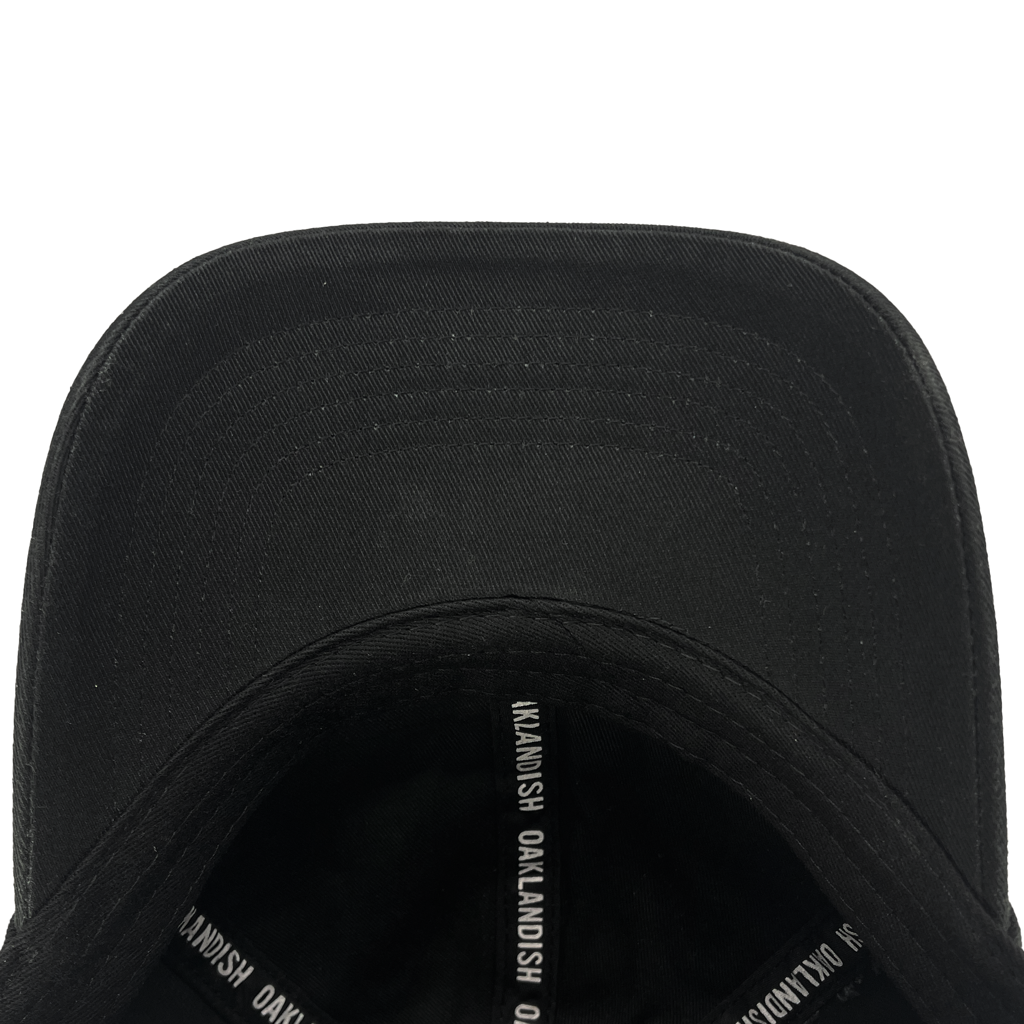 A close-up view of the Oakland Ballers Dad Hat, showcasing the underside of the brim and interior taping labeled "OAKLANDISH" in white text. The smooth black fabric and detailed stitching on the brim are clearly visible. Perfect for an Oakland Ballers fan, this hat embodies a community-focused experience.