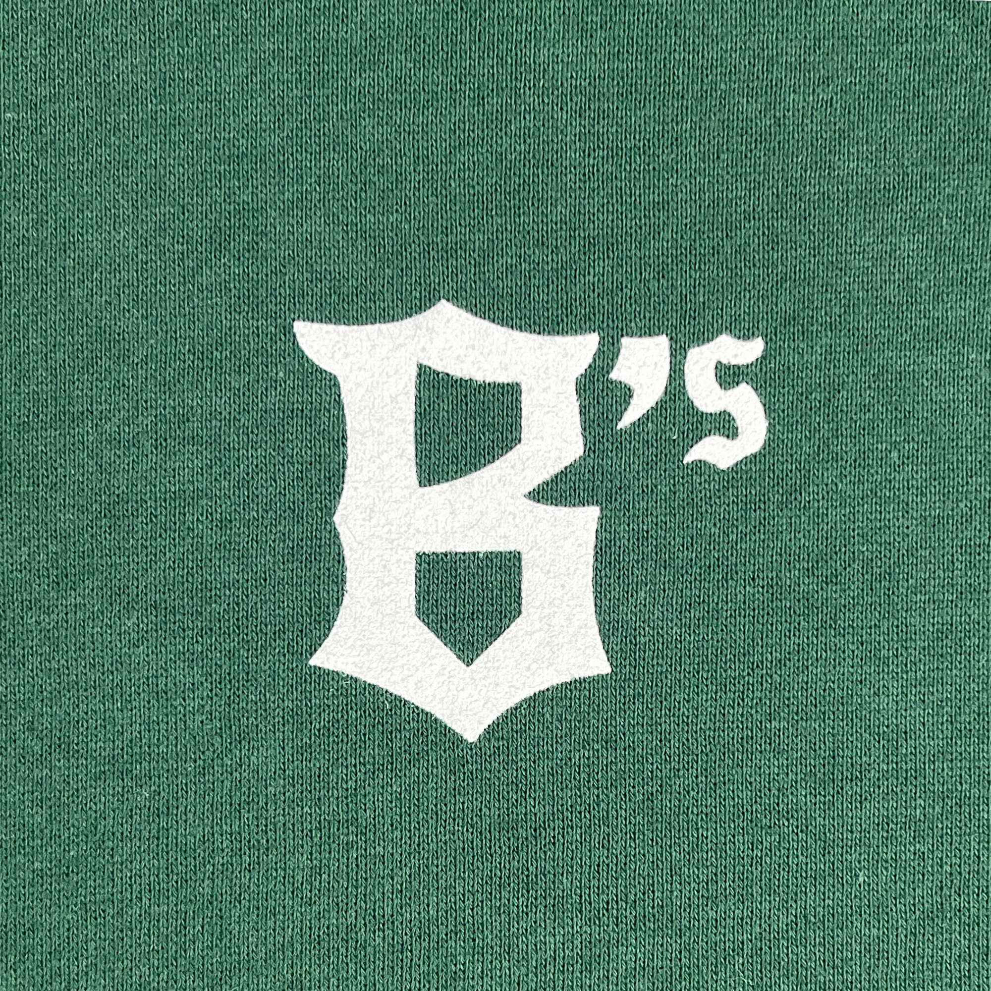 A green textured background showcasing the bold, white Oakland Ballers logo with a stylized "B" featuring sharp edges. Adjacent to the "B" is an apostrophe followed by the lowercase letter "s," rendered in a simpler font. This design elegantly pays homage to Oakland's new pro baseball team, as seen on the Oakland Ballers Logo Heavyweight Hoodie from Oakland Ballers.