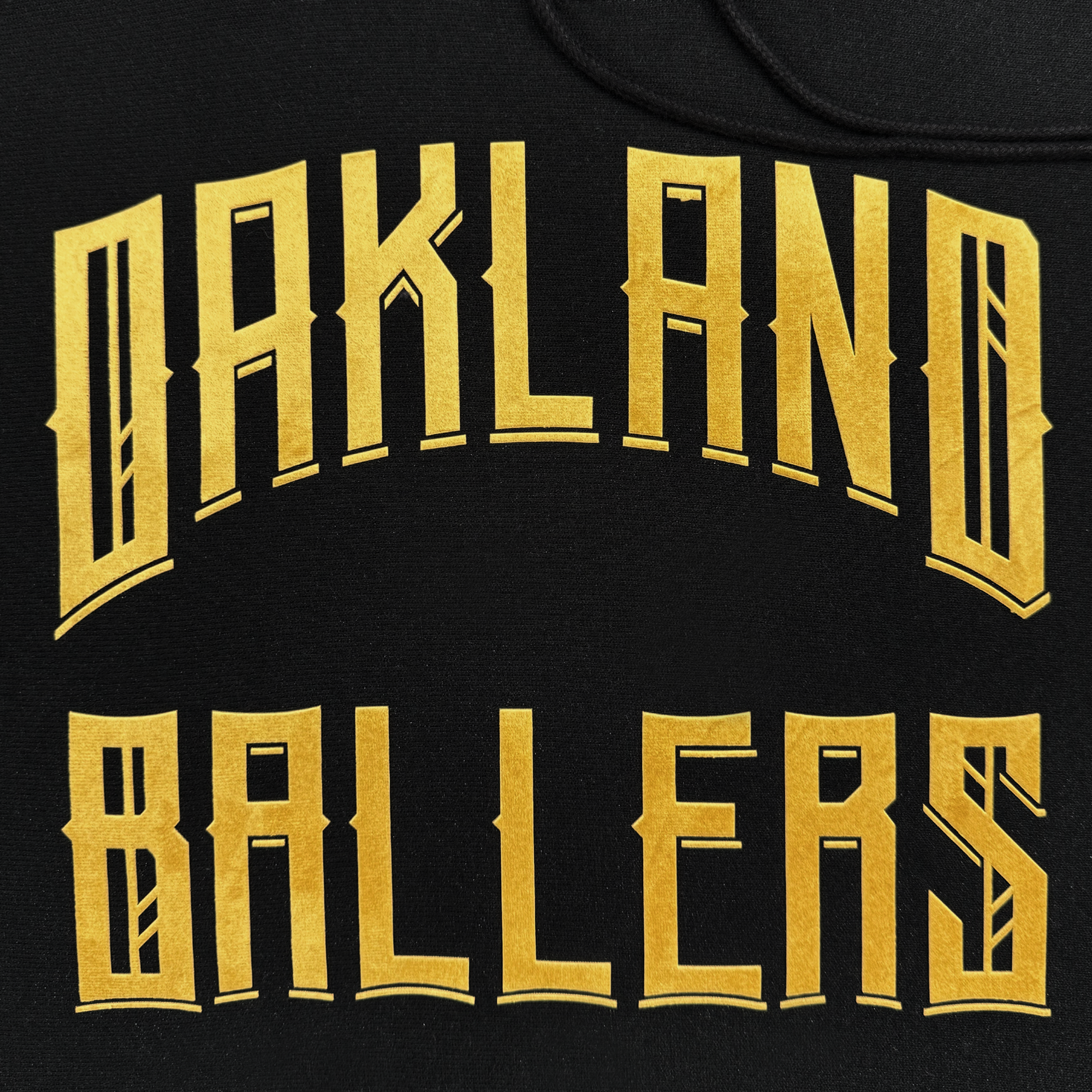 The Champion X Oakland Ballers Hoodie features "OAKLAND BALLERS" in bold, gold geometric font on a plain black background, celebrating the new pro baseball team with its sporty and urban style.