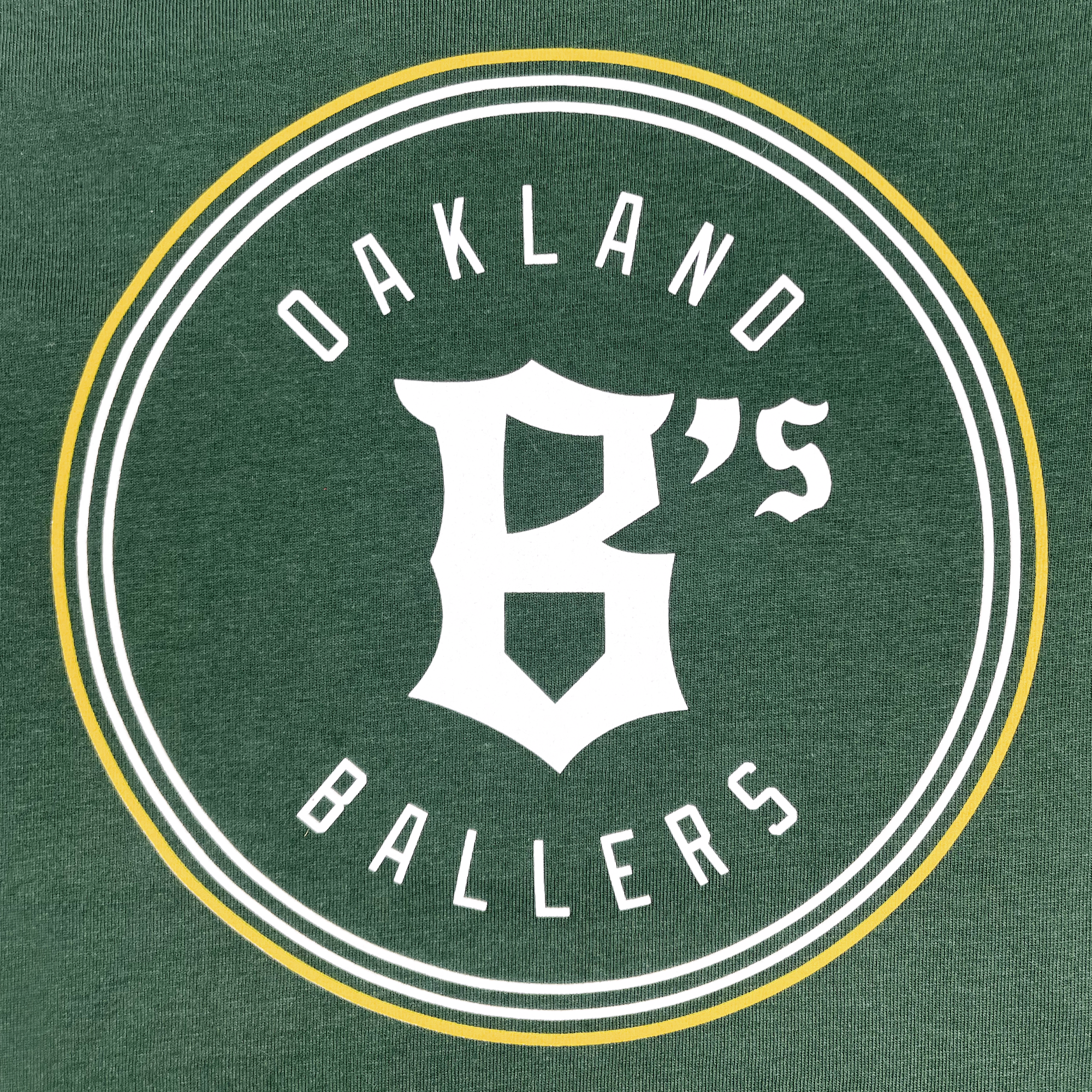 The Youth Oakland Ballers Logo Hoodie features a green logo with the text "Oakland Ballers" encircling a white, stylized "B" in the center. The design represents this professional baseball team and includes a double-lined circle, with the inner line being thicker and a yellow accent circle around the outer edge.