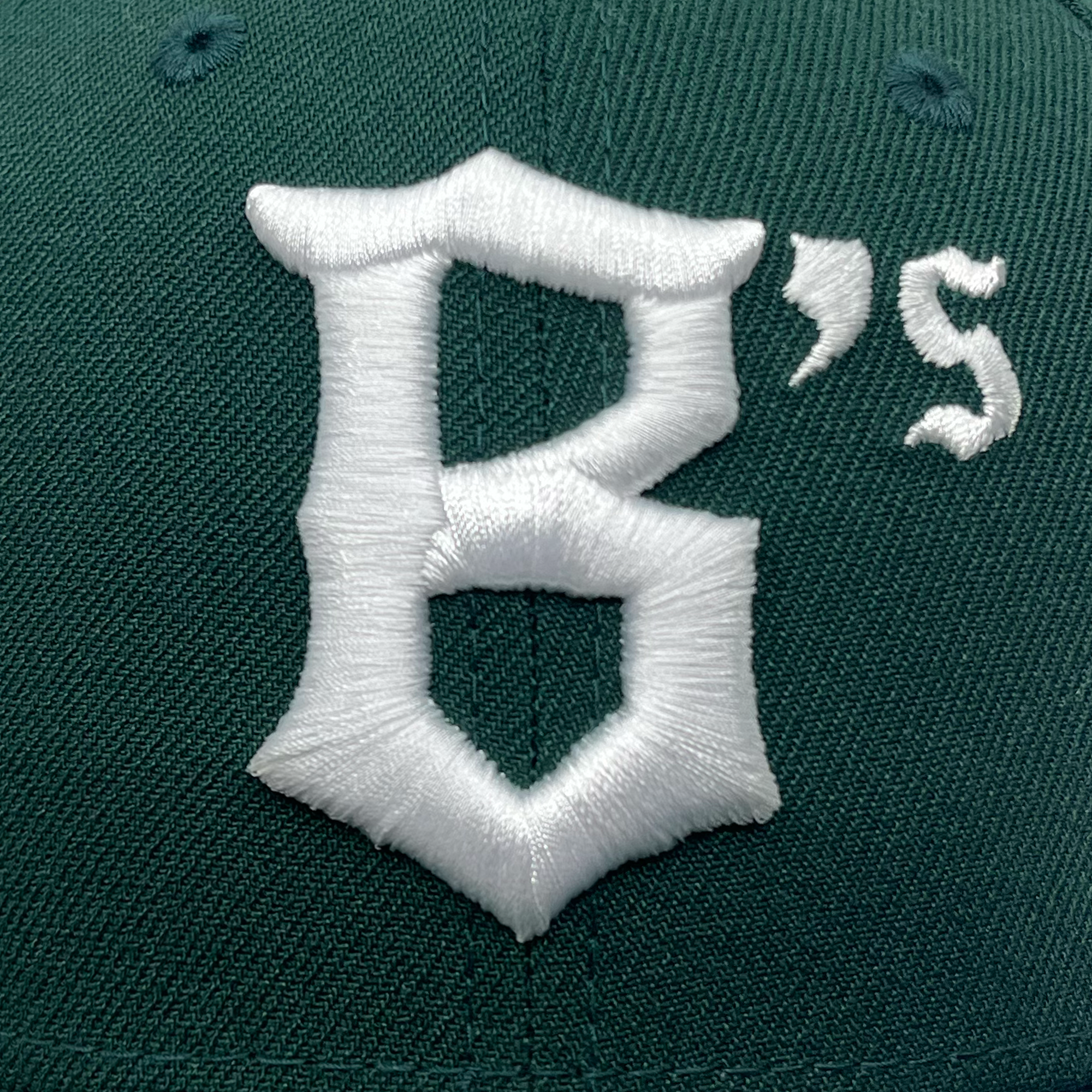 A close-up view of the New Era Oakland Ballers Low Profile 59FIFTY Cap, showcasing its vibrant green color and prominently embroidered white "B's" logo. The detailed stitching highlights the cap’s high-quality craftsmanship. The material has a textured, woven appearance typical of baseball caps, making it an ideal choice for fans of the Pioneer League team, Oakland Ballers.