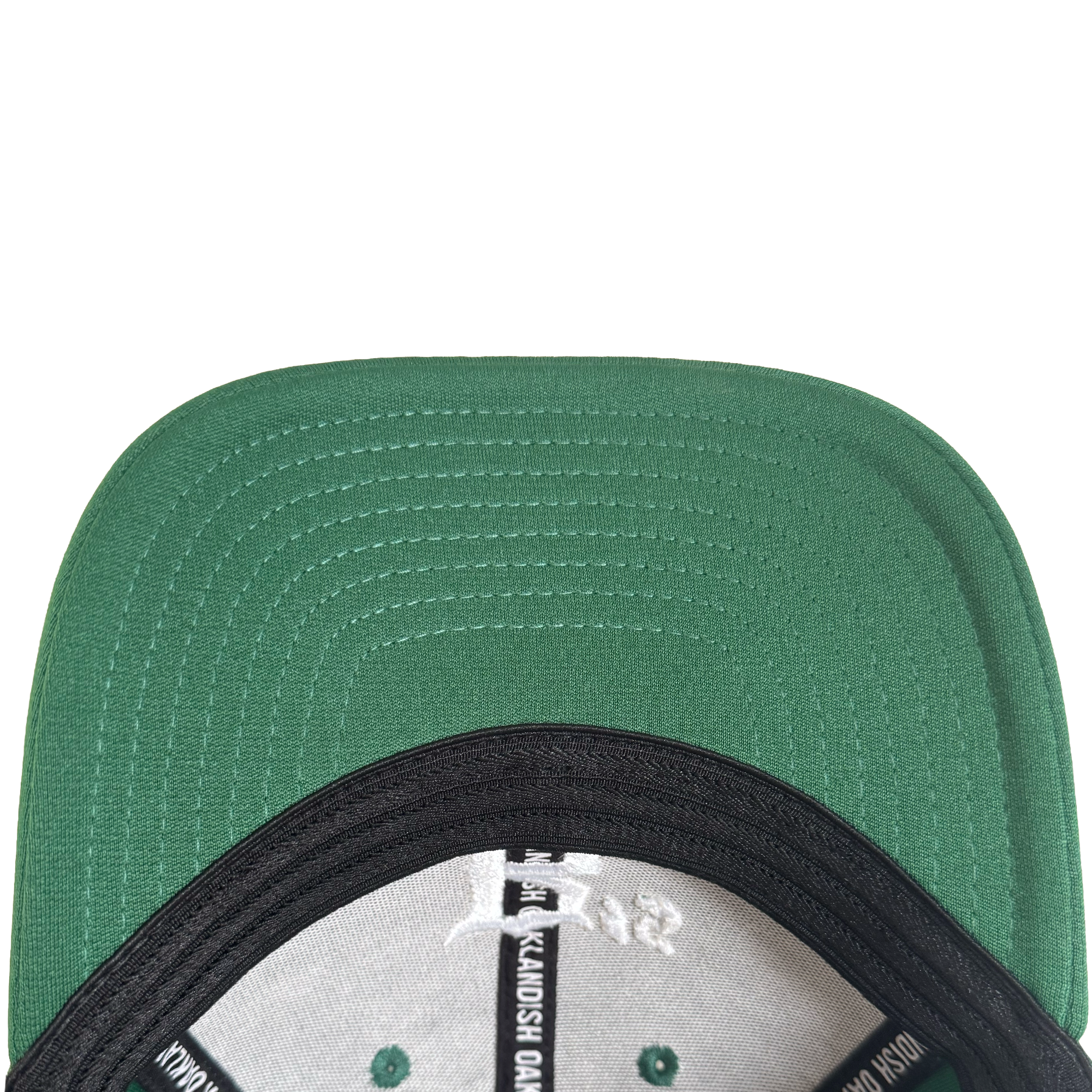 Close-up, top-down view of the Oakland Ballers Logo Flexfit Hat. The green flat brim shows stitched lines underneath, and inside are black and white labels with seams. The background is white. Brand: Oakland Ballers.