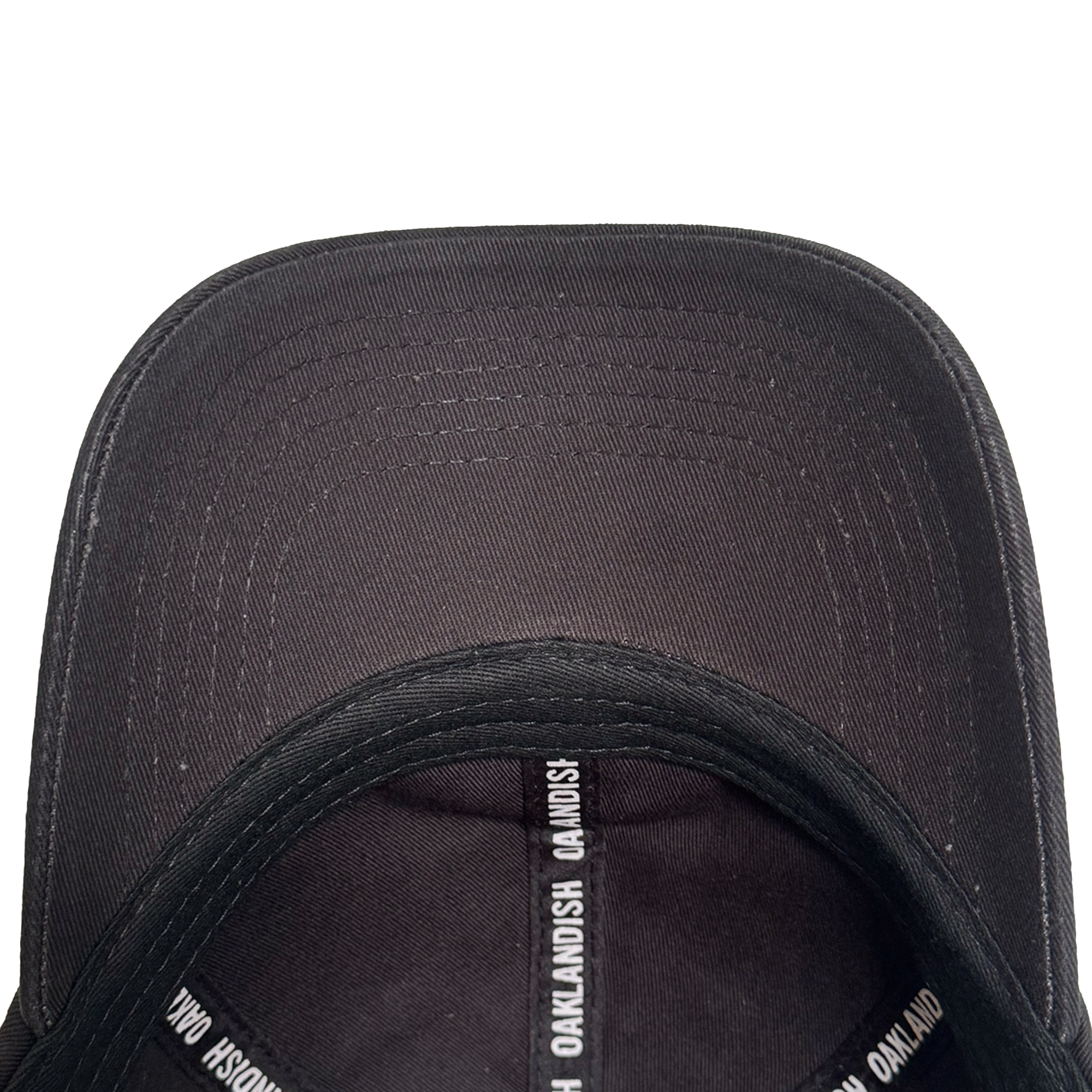 Top-down view of the inside of the AC Transit Dad Hat by Oaklandish. The inner seams feature repeating white "OAKLANDISH" text, celebrating East Bay pride. Its curved brim and stitching details stand out against a plain white background.